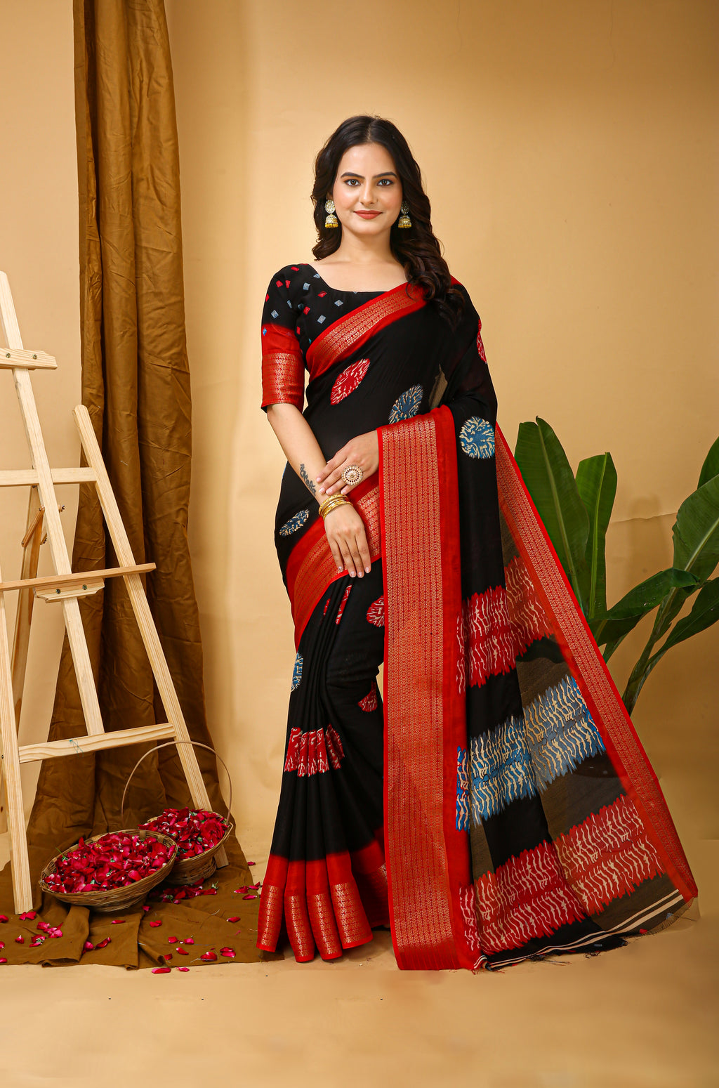 Woman wearing a black and red saree with a decorative border against a beige background