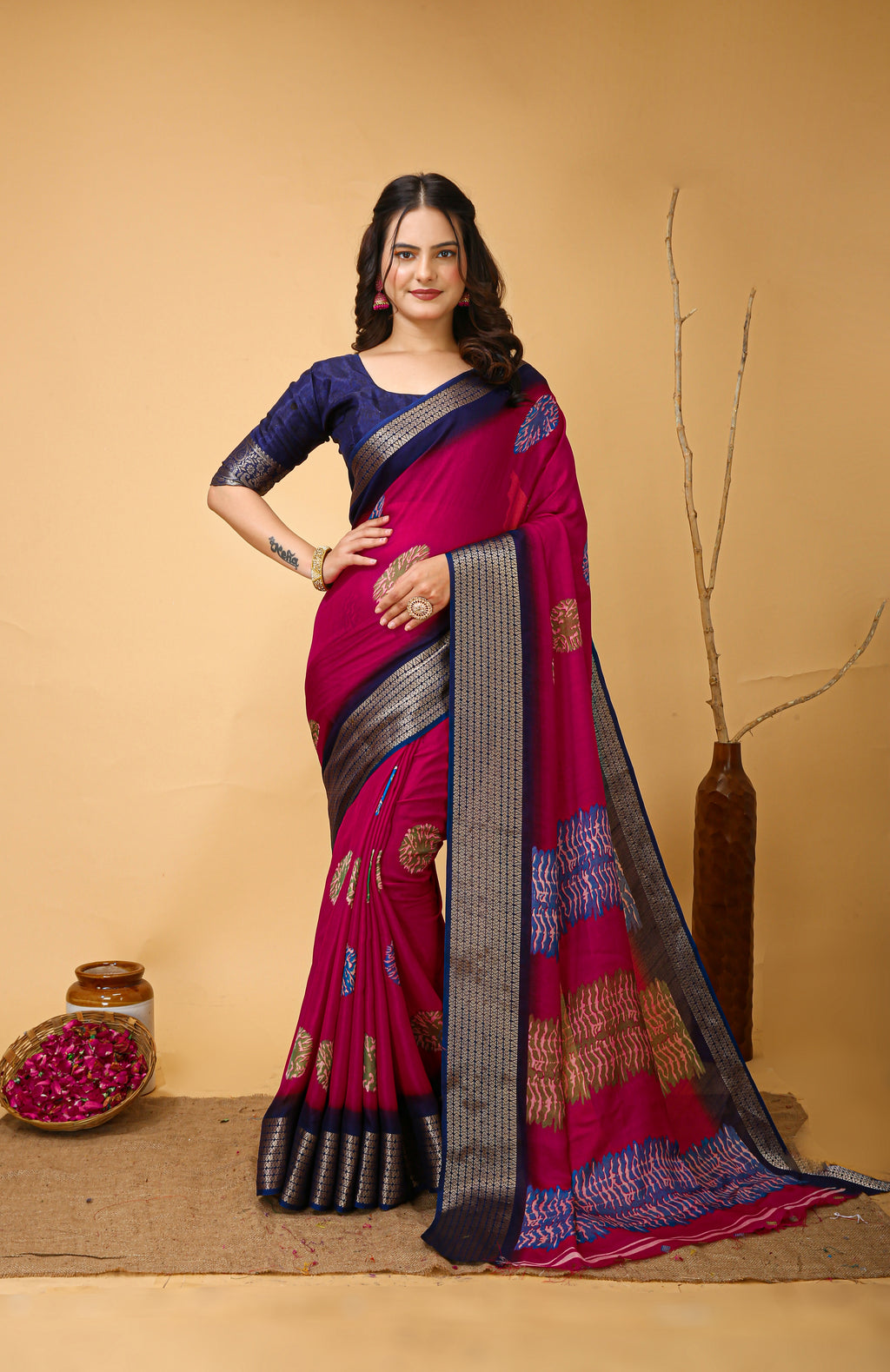 Woman wearing a pink saree with a blue border on a beige background