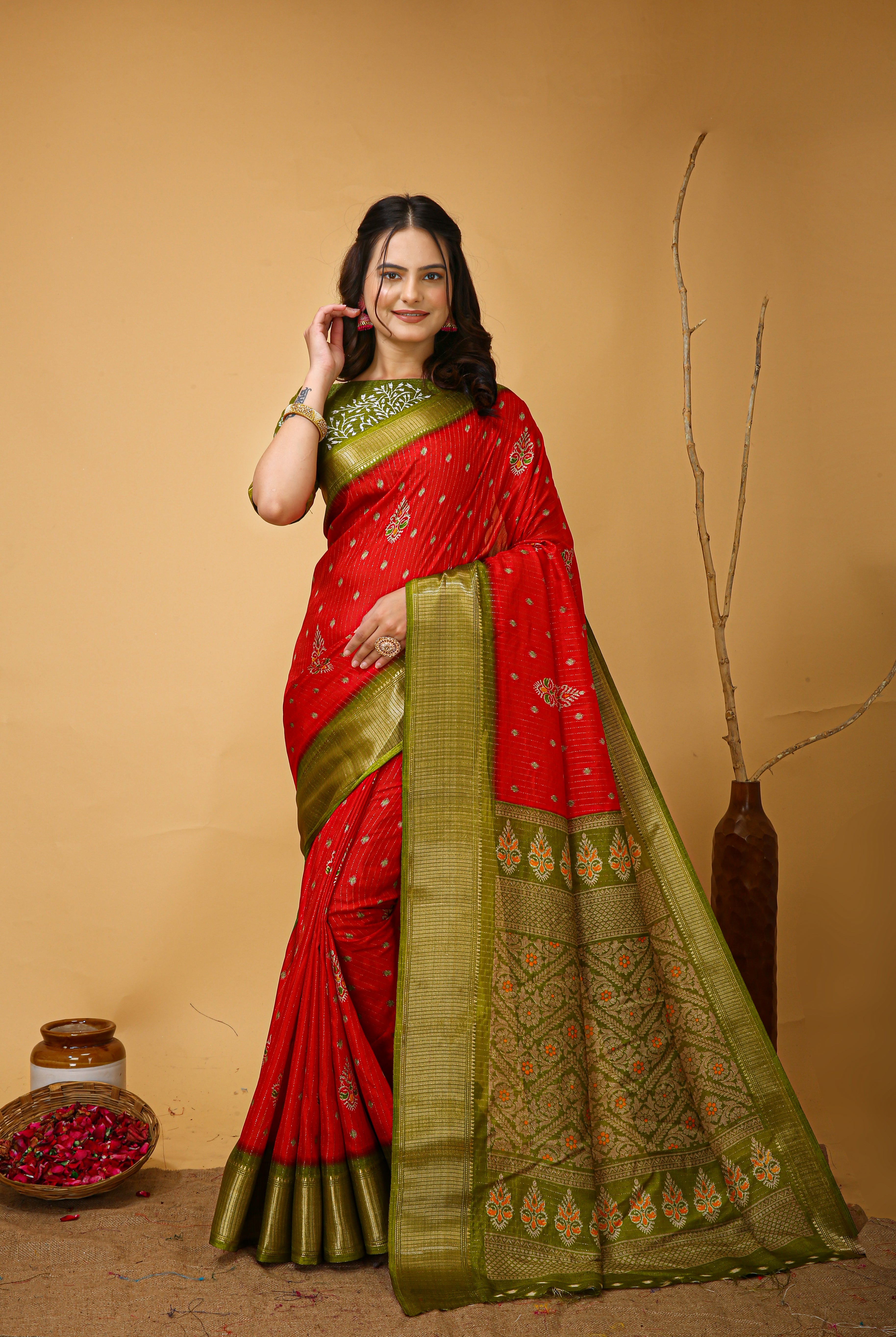 Woman wearing a red and green saree with a beige background