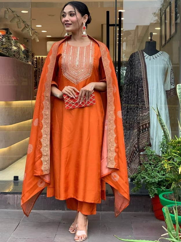 Woman in an orange traditional outfit standing in front of a store window display.