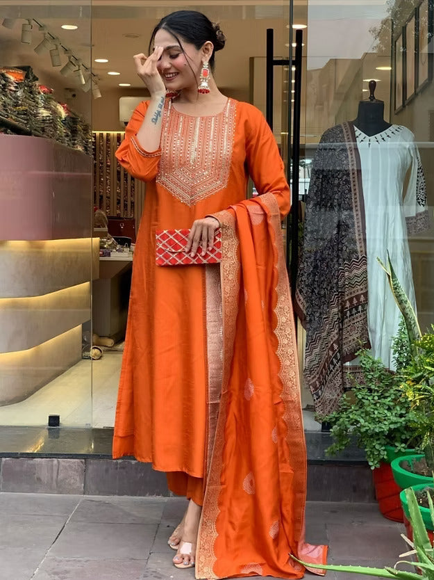 Woman in an orange traditional outfit standing in front of a store with mannequins.