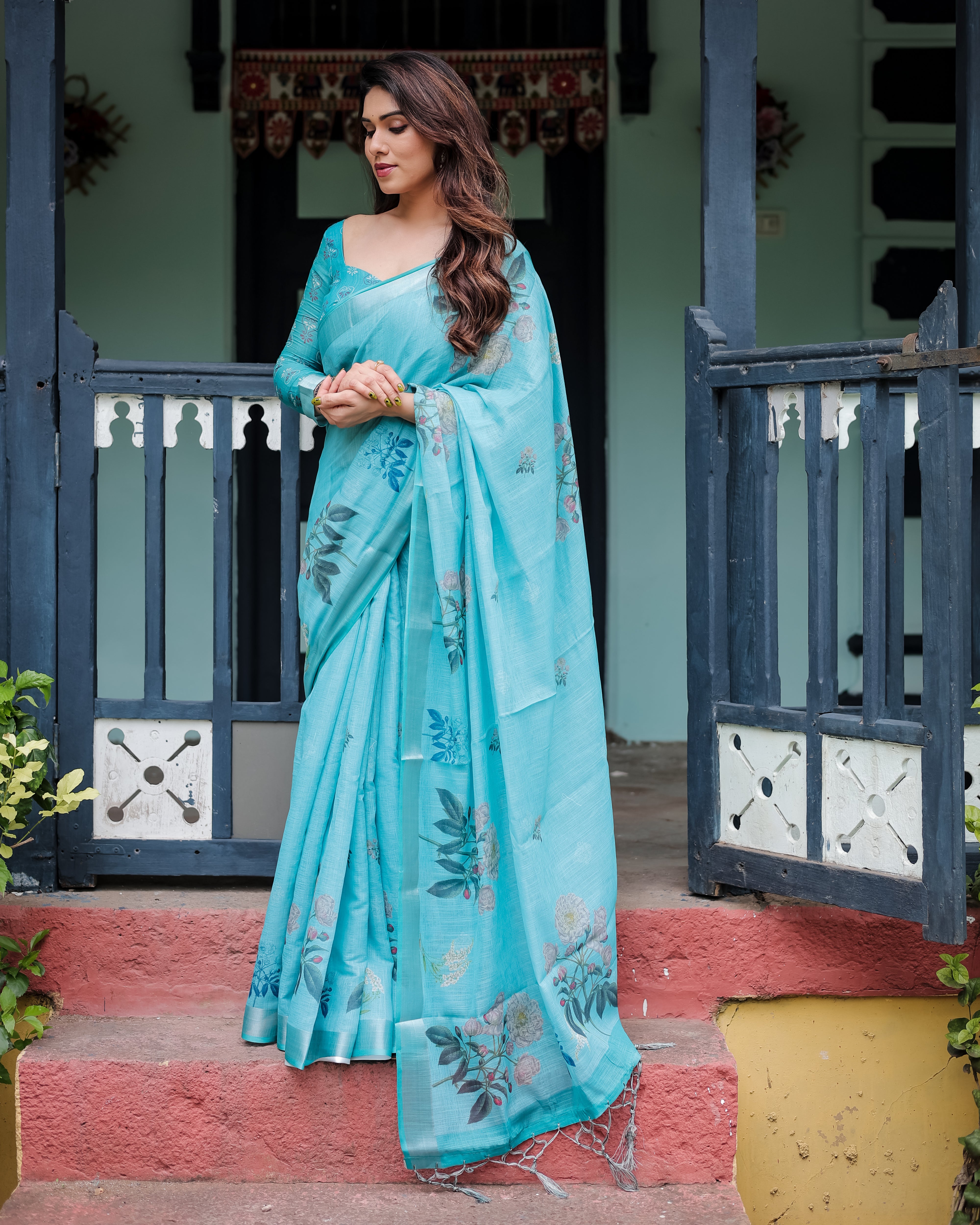 Woman in a aqua blue saree standing on a porch.