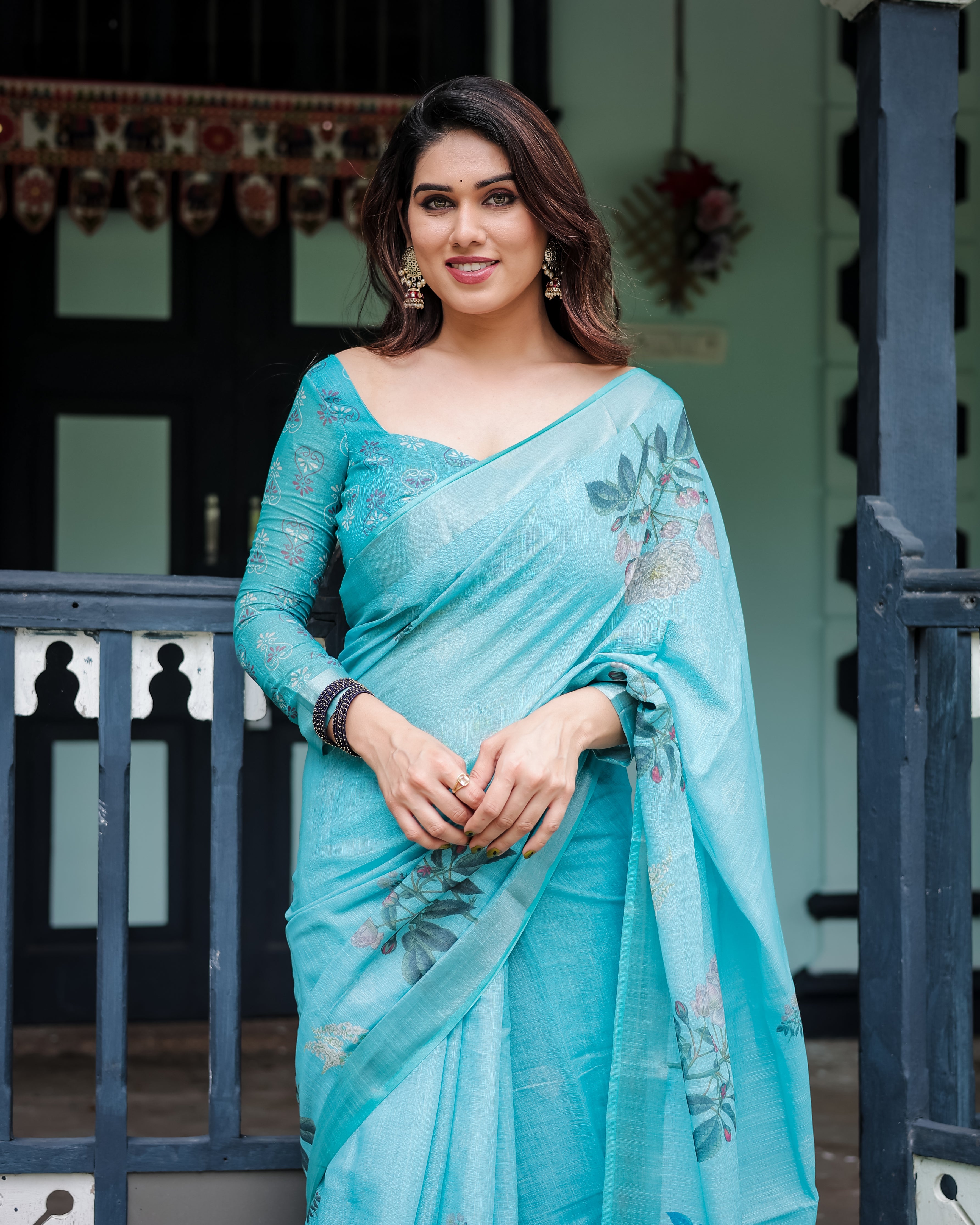 Woman wearing a light blue saree with floral patterns in an outdoor setting.