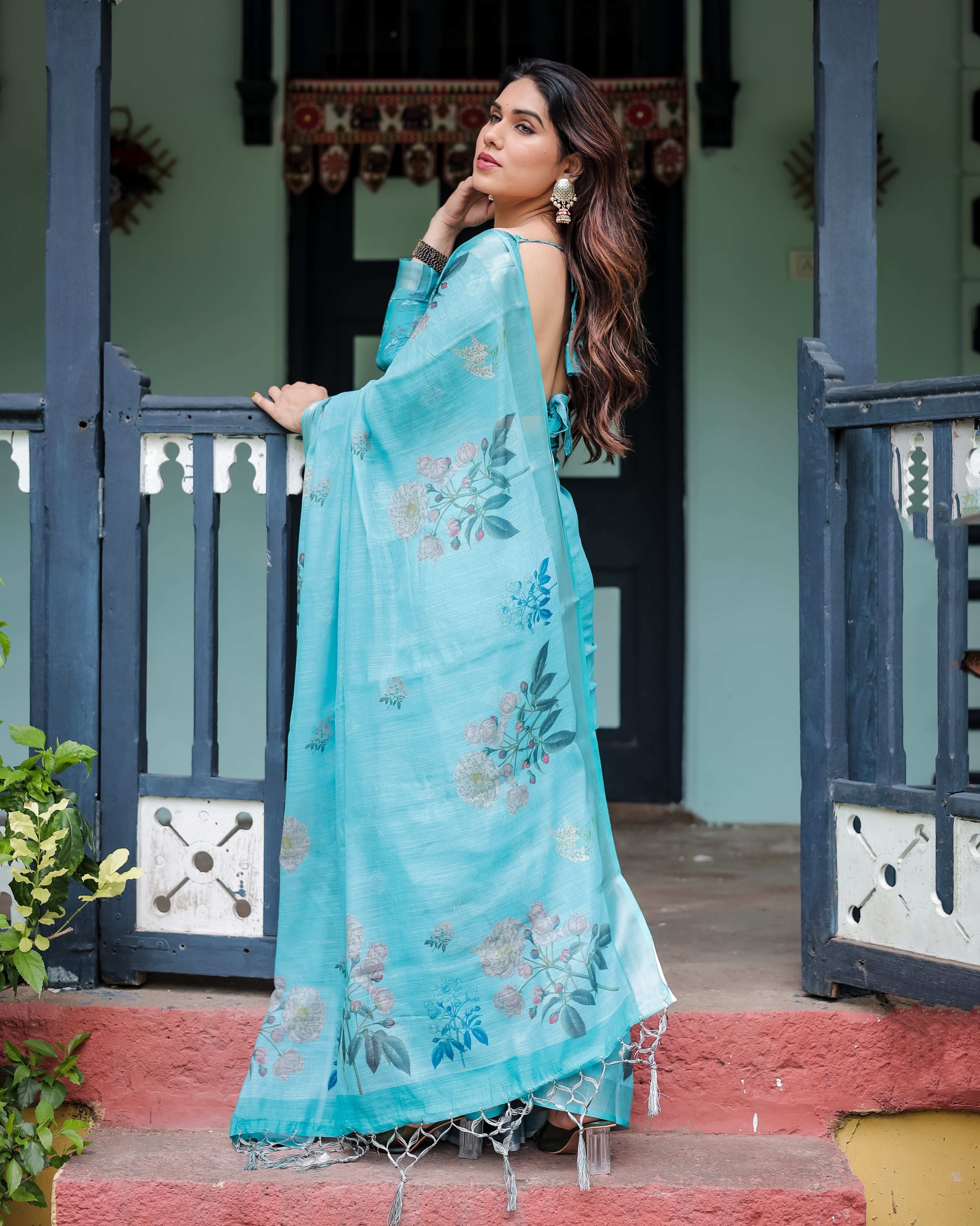 Woman in a blue floral dress standing on steps with a decorative background