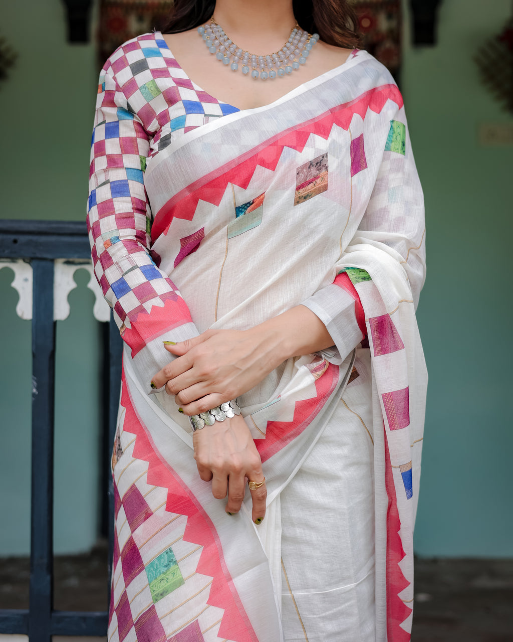 Person wearing a colorful saree with a patterned blouse against a blurred background