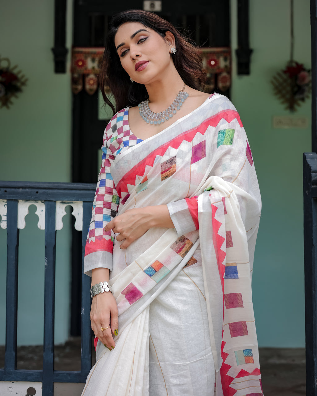 Woman wearing a white saree with colorful patterns in an outdoor setting