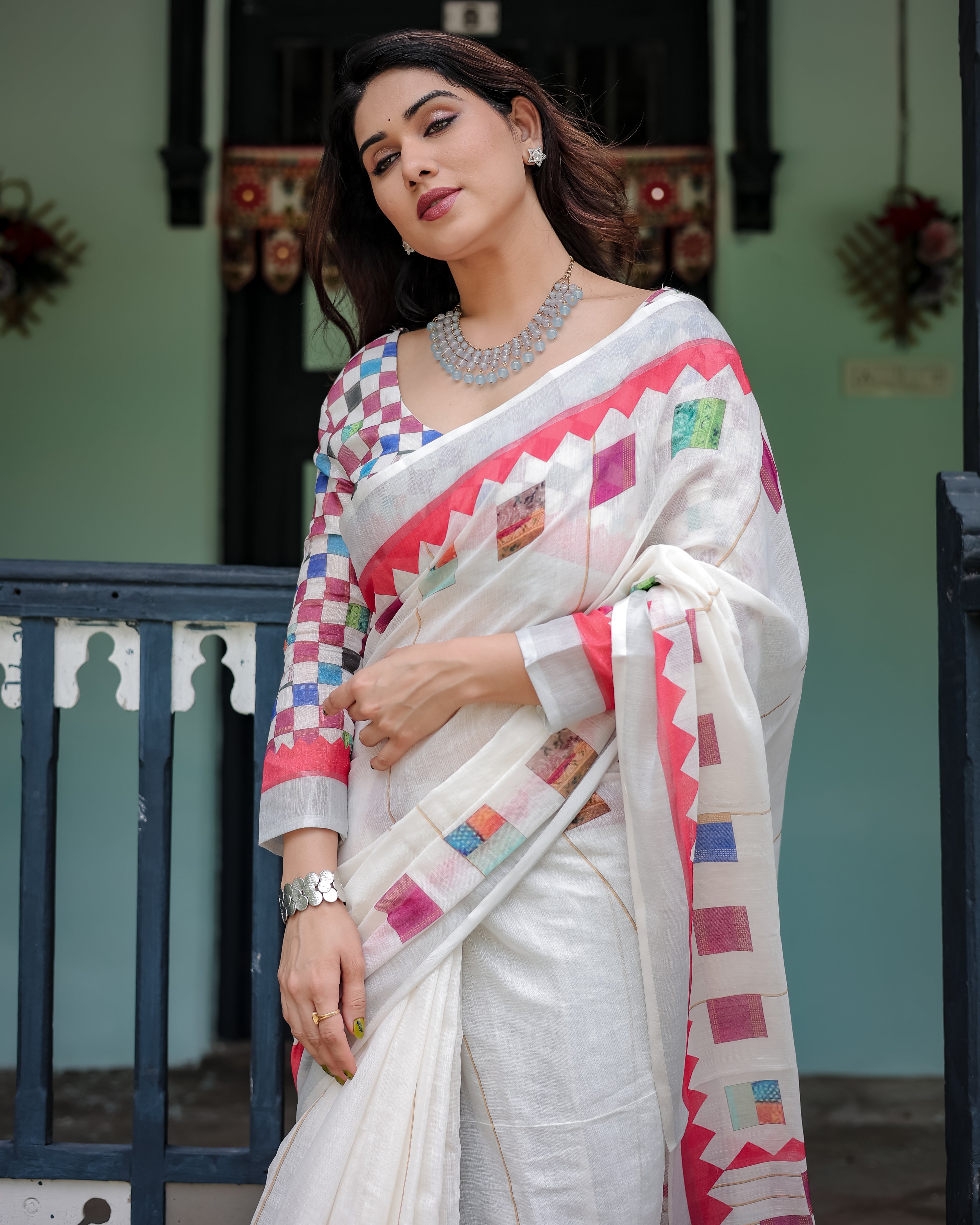 Woman wearing a white saree with colorful patterns in an outdoor setting