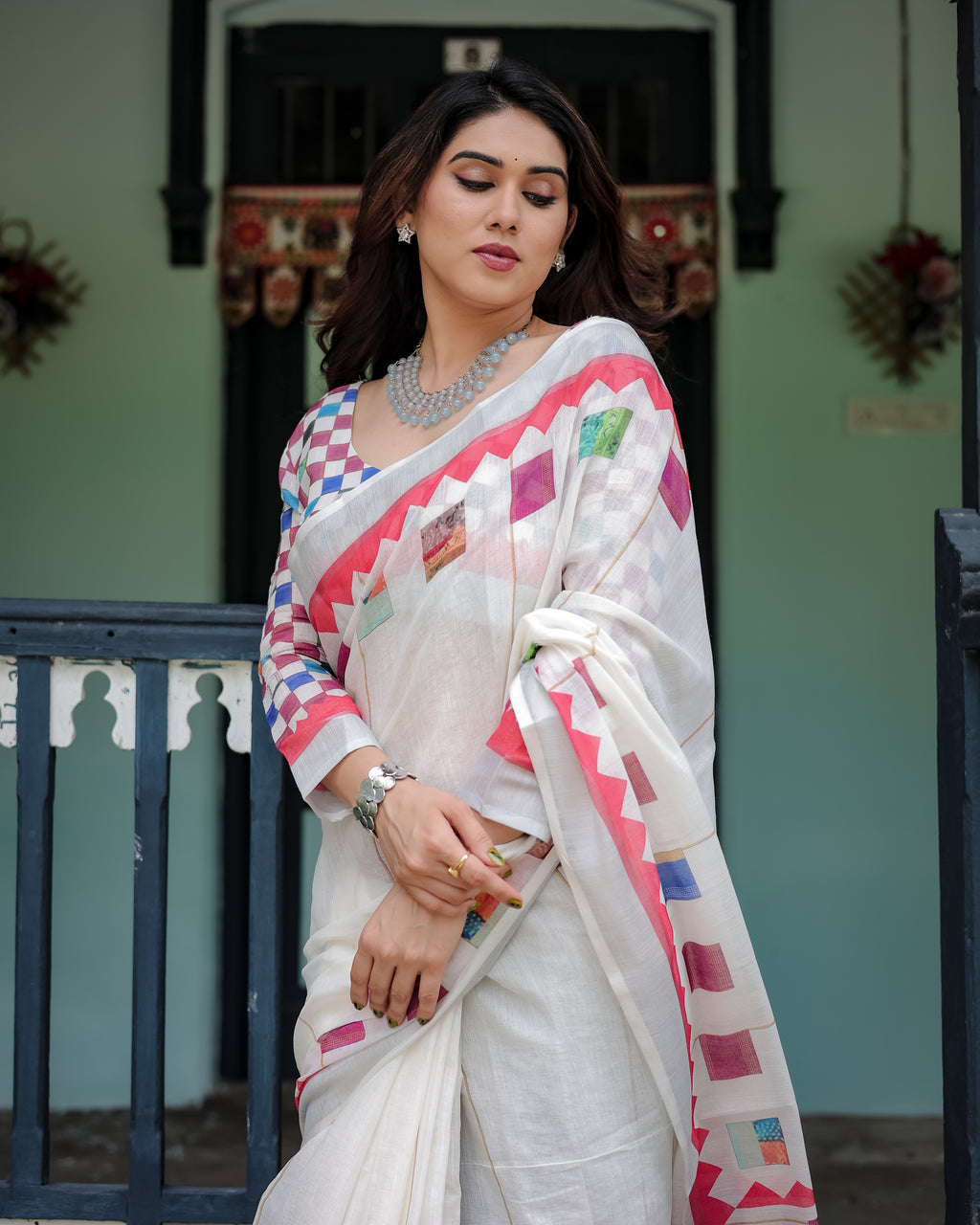 Woman wearing a white saree with colorful patterns in an outdoor setting
