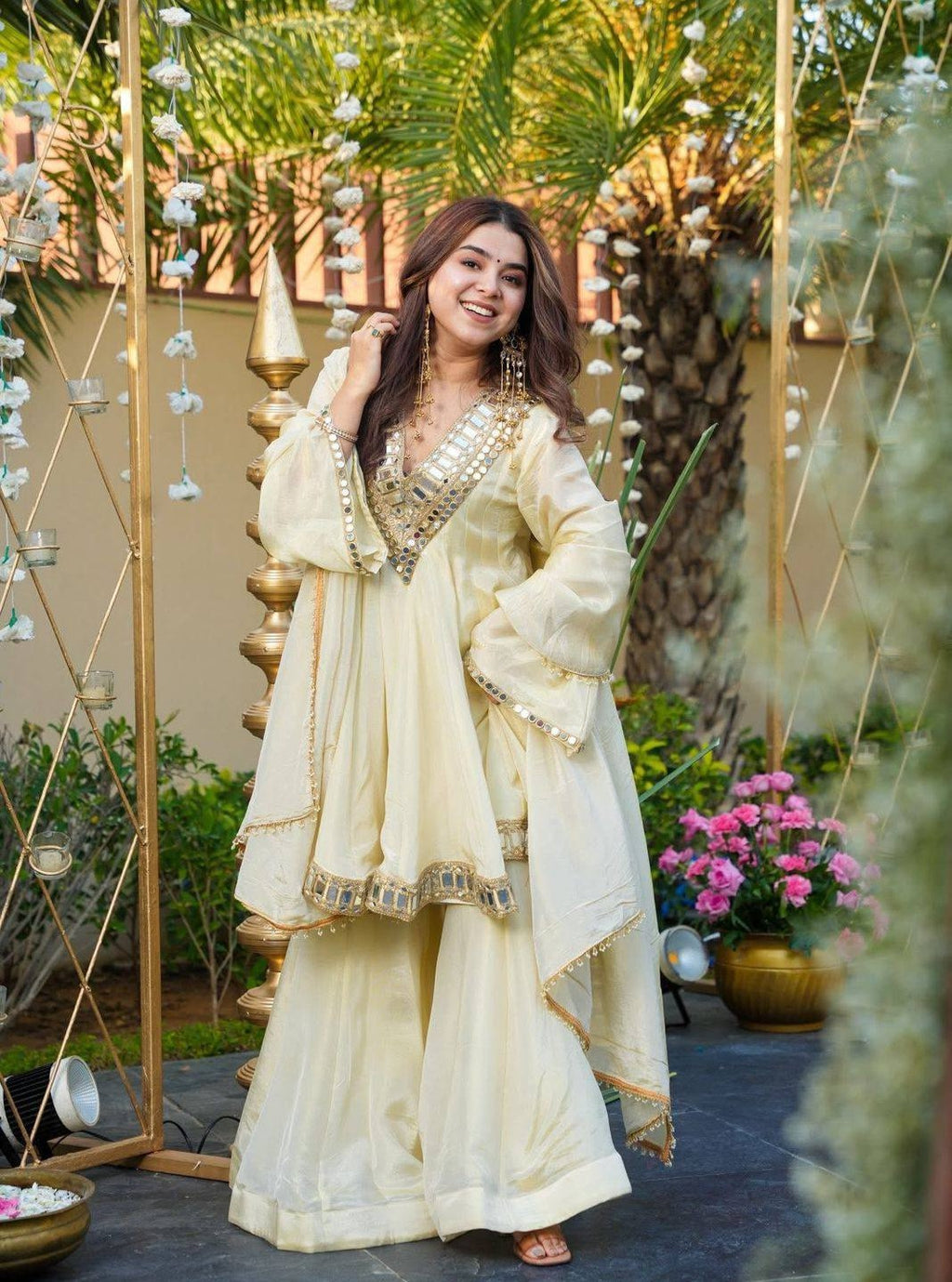 Woman in a traditional Kurta Plazo Set outfit standing in an outdoor setting with decorative elements.