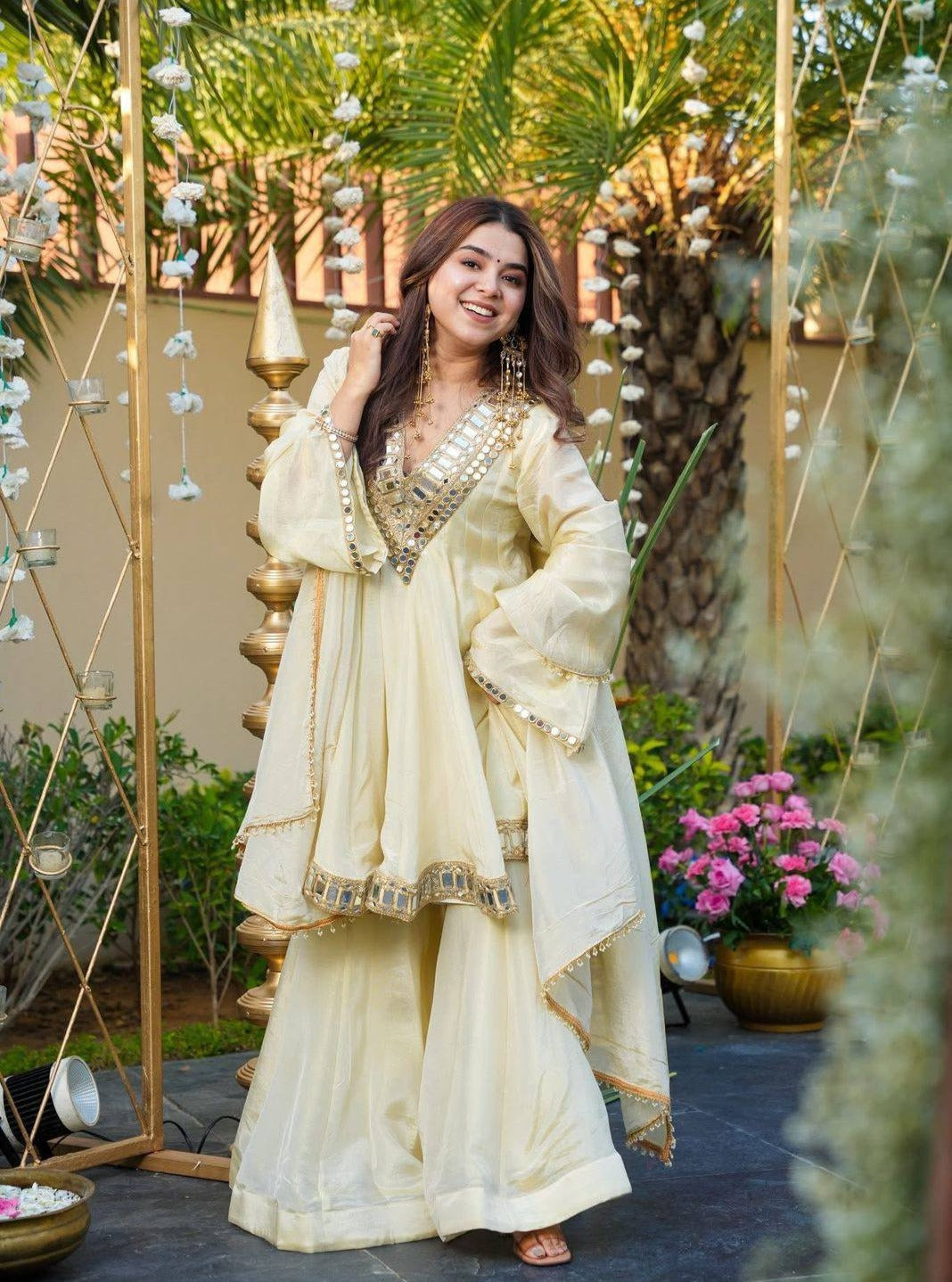 Woman in a traditional Kurta Plazo Set outfit standing in an outdoor setting with decorative elements.