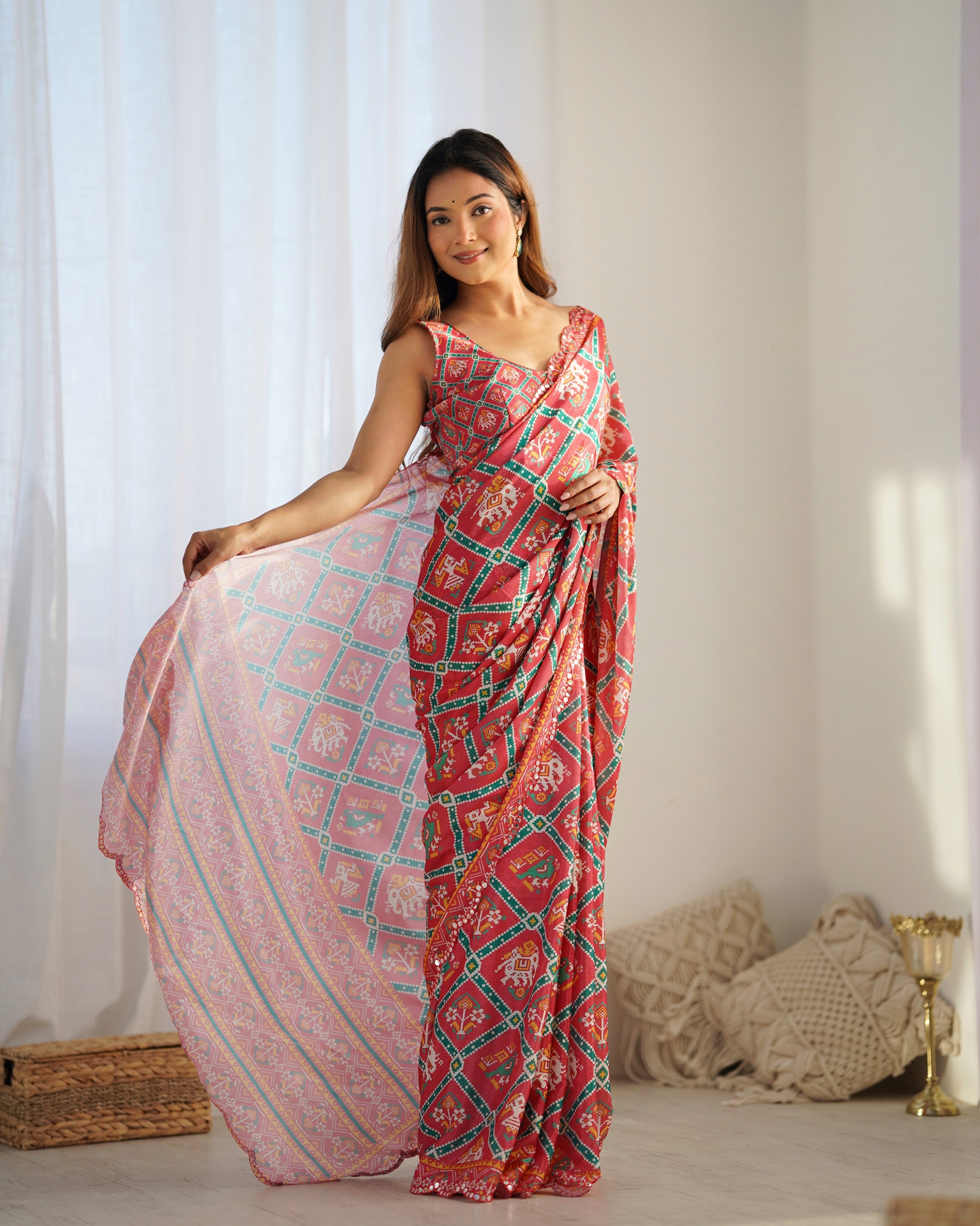 Woman wearing a green and pink patterned saree in a bright room.