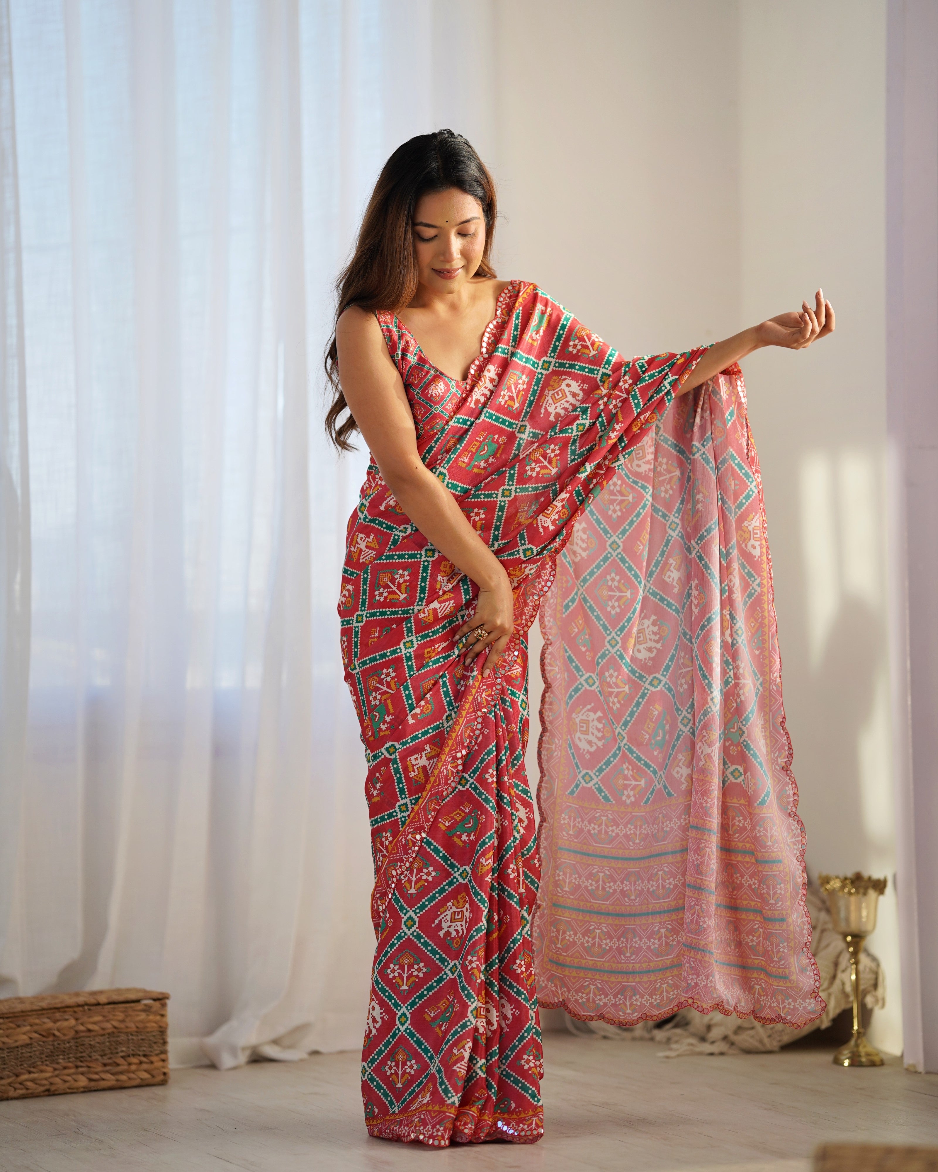 Woman wearing a red patterned saree with a white background