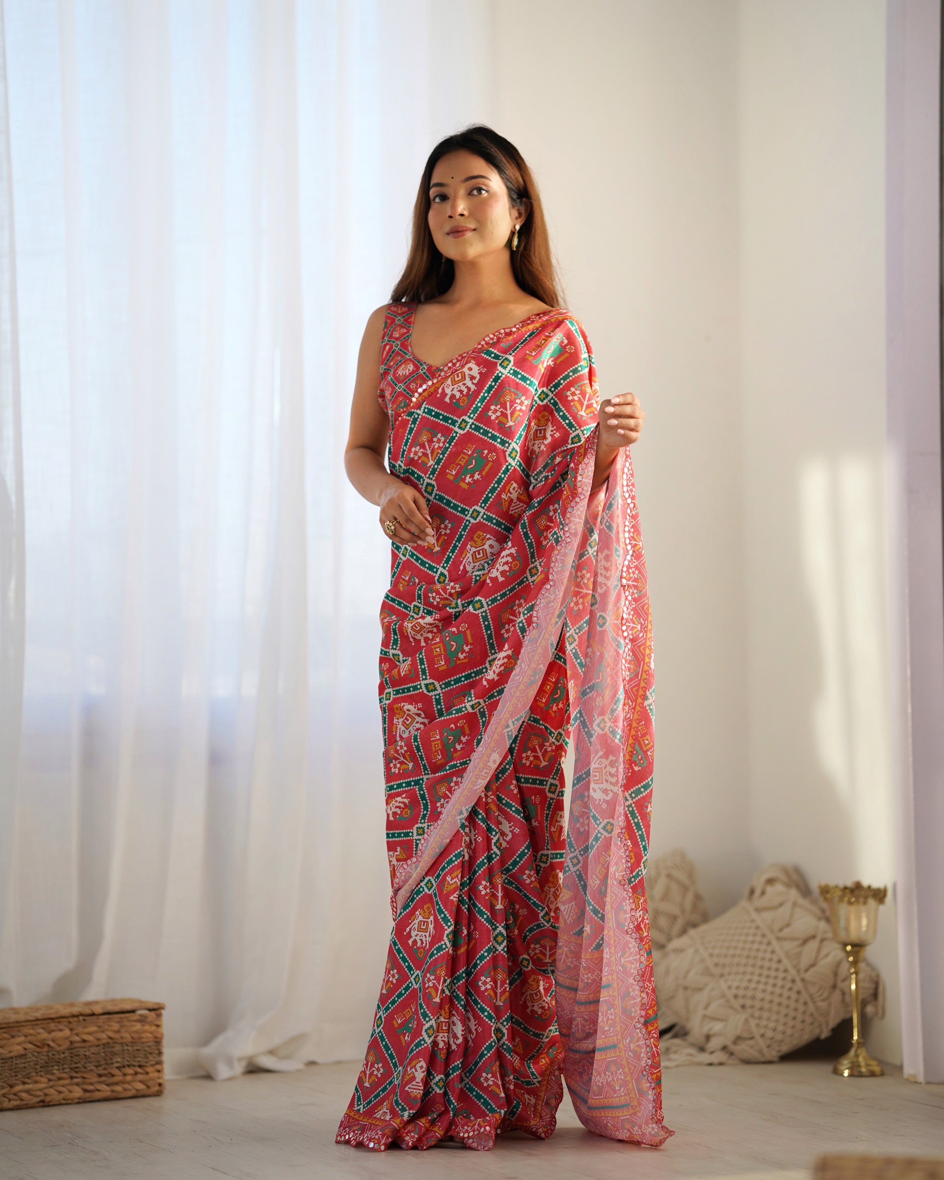 Woman wearing a pink and green patterned saree with a white background