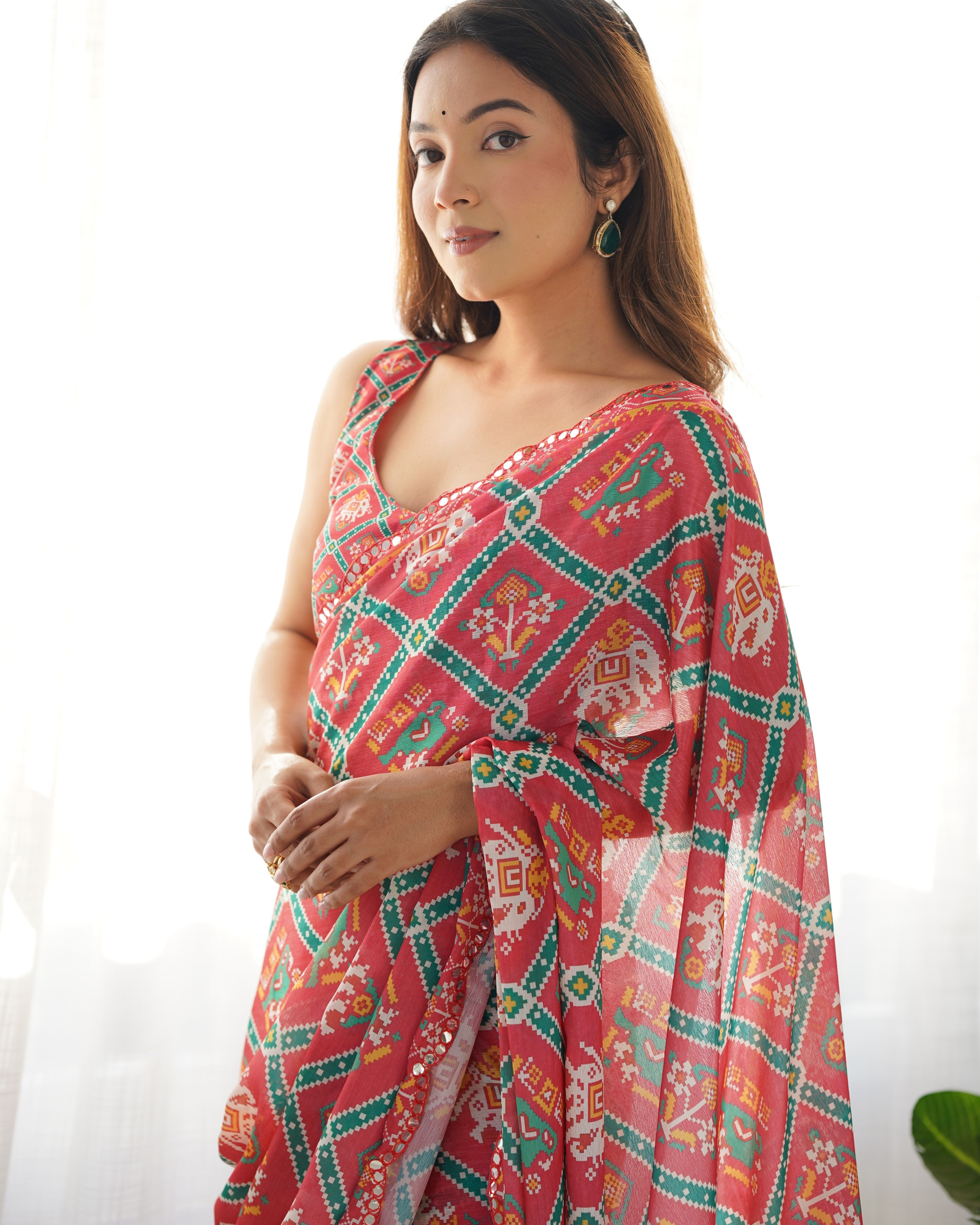 Woman wearing a pink and green patterned saree on a white background