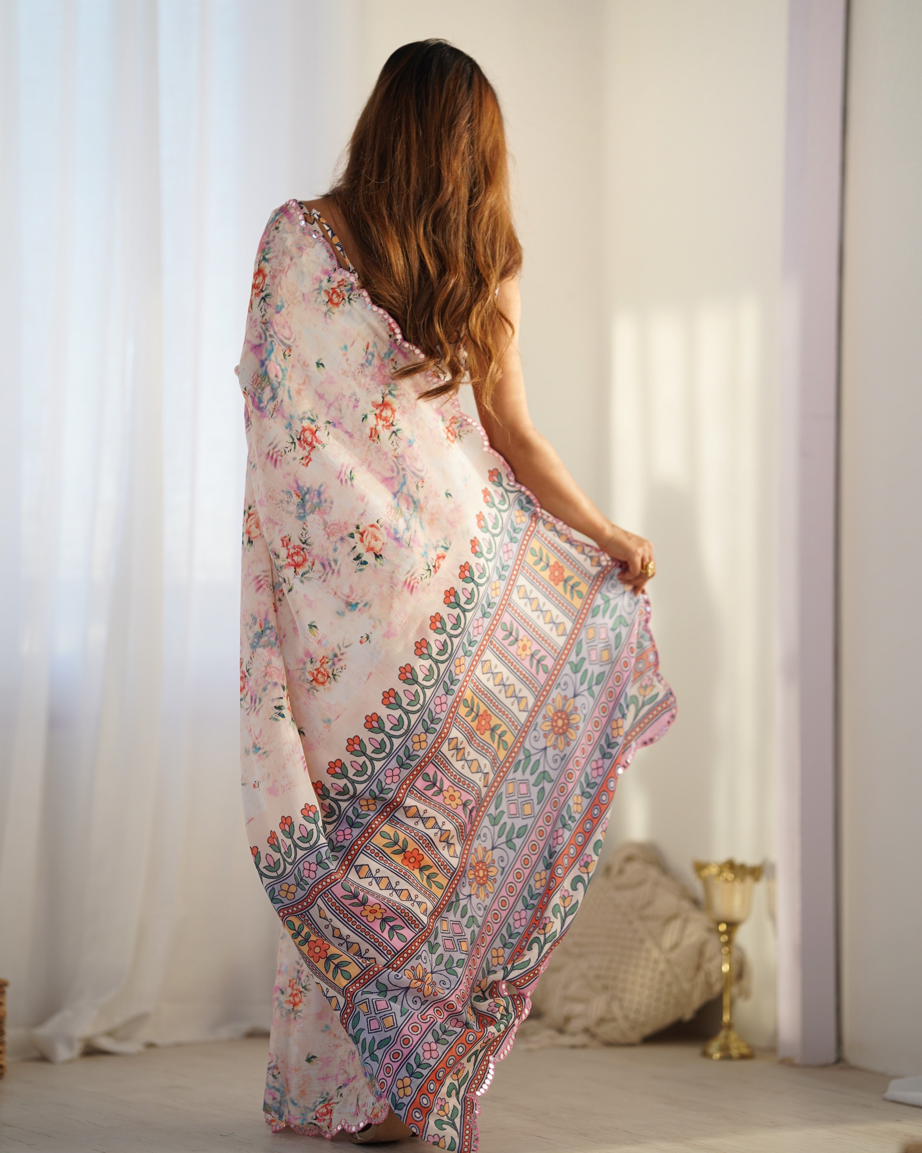 Woman holding a colorful floral and paisley patterned scarf in a bright room.