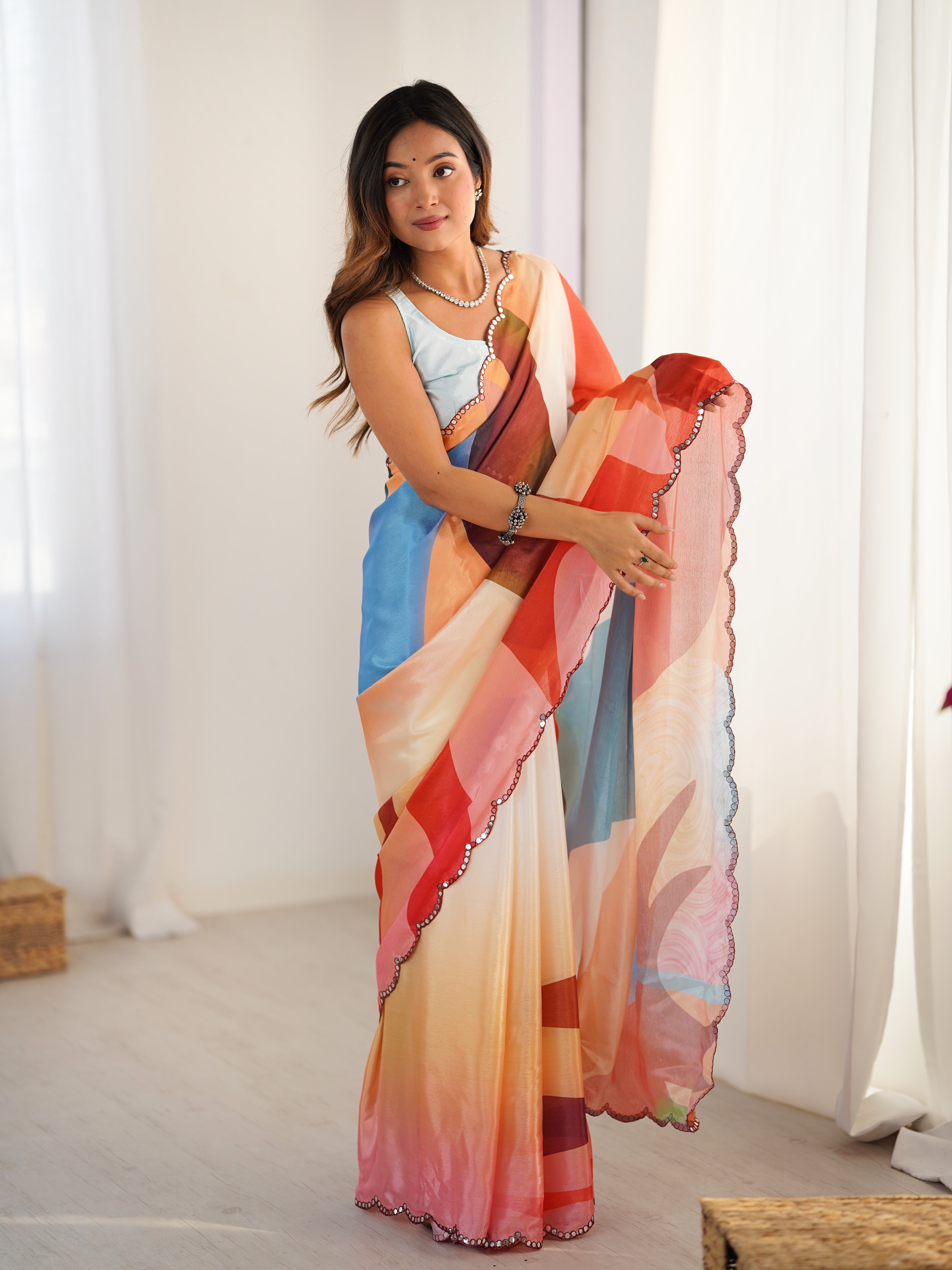 Woman holding a colorful saree in a bright room