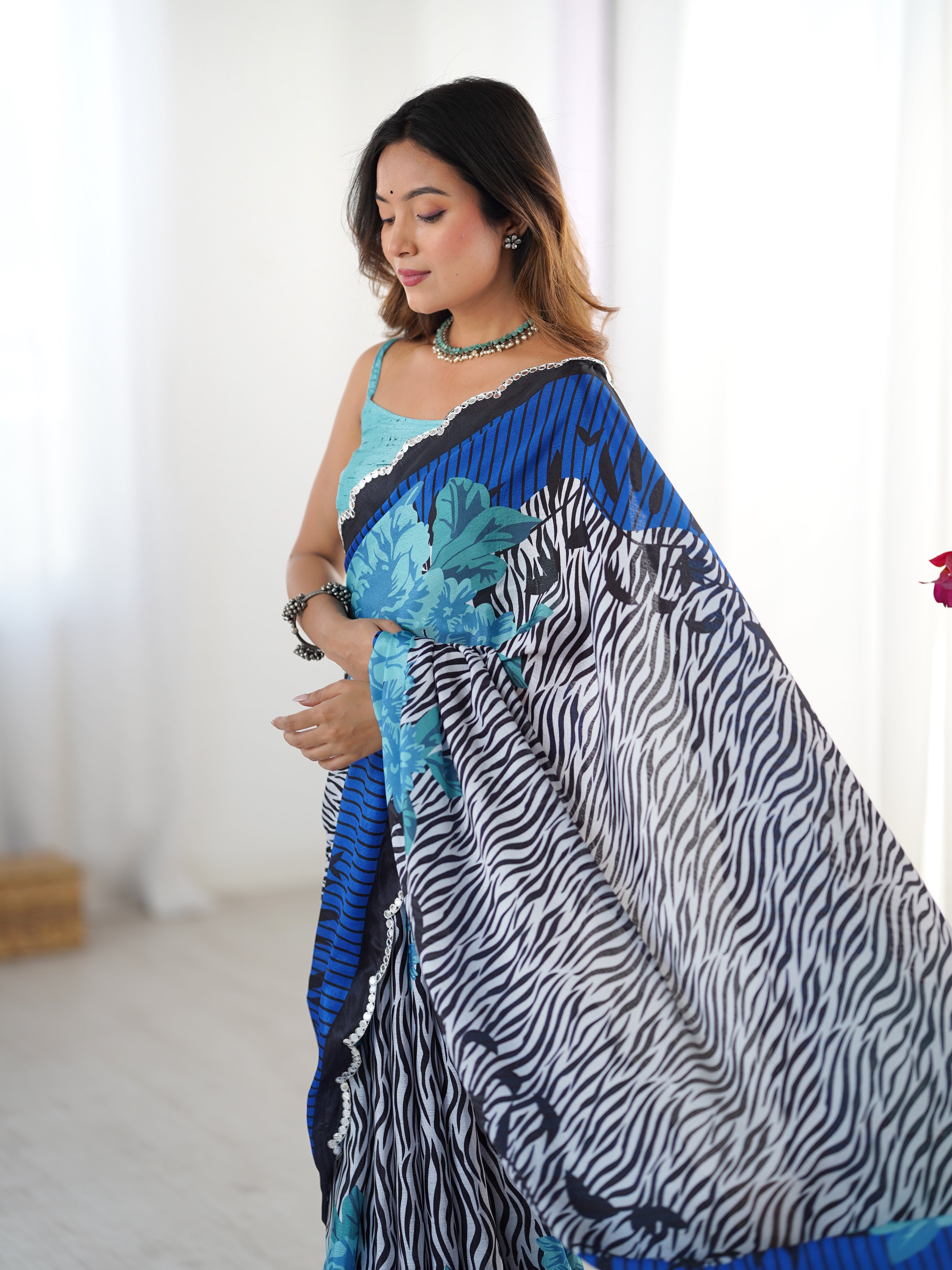 Woman wearing a blue and black patterned saree with a white background