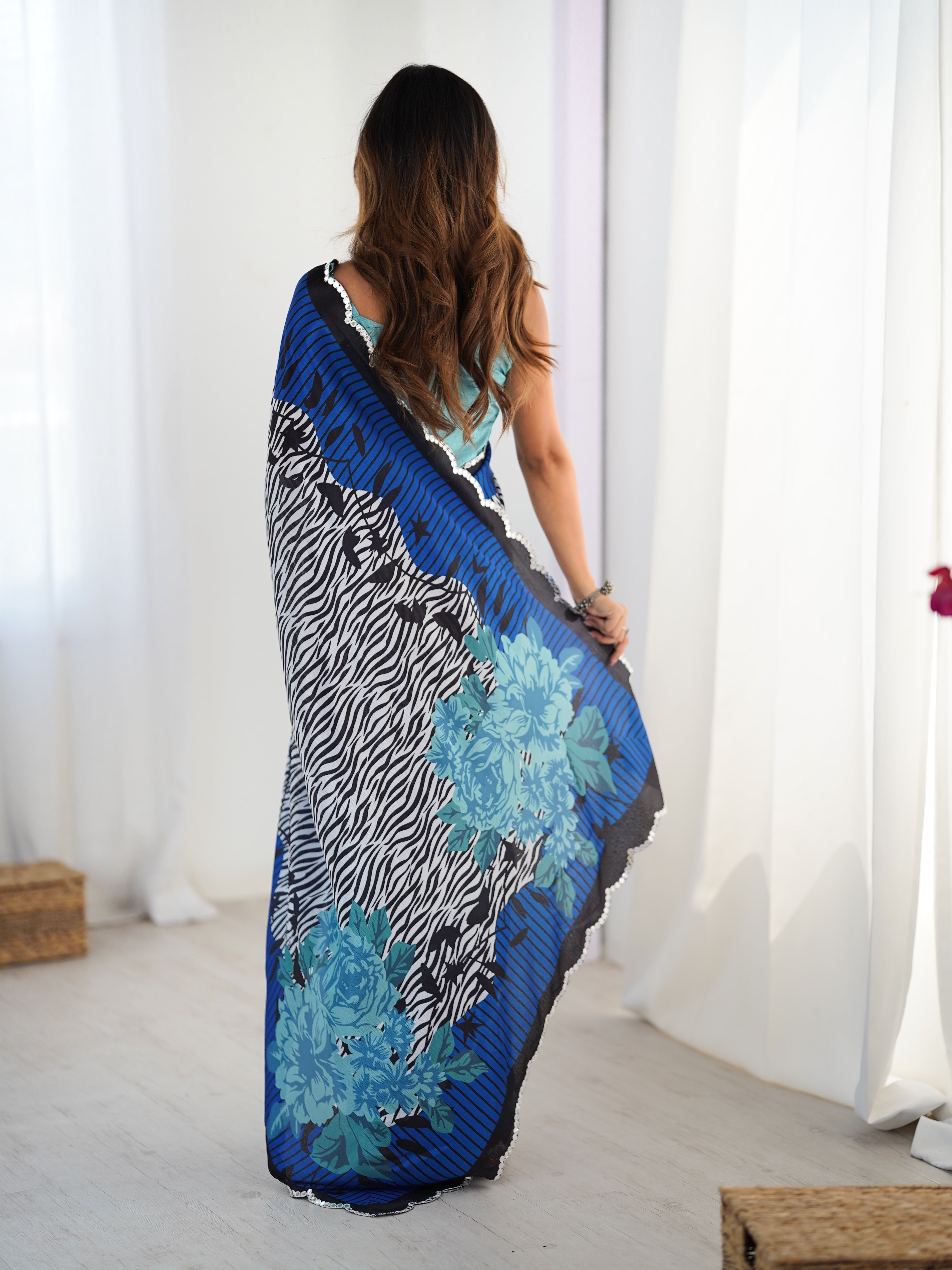 Woman holding a colorful patterned fabric against a white curtain background