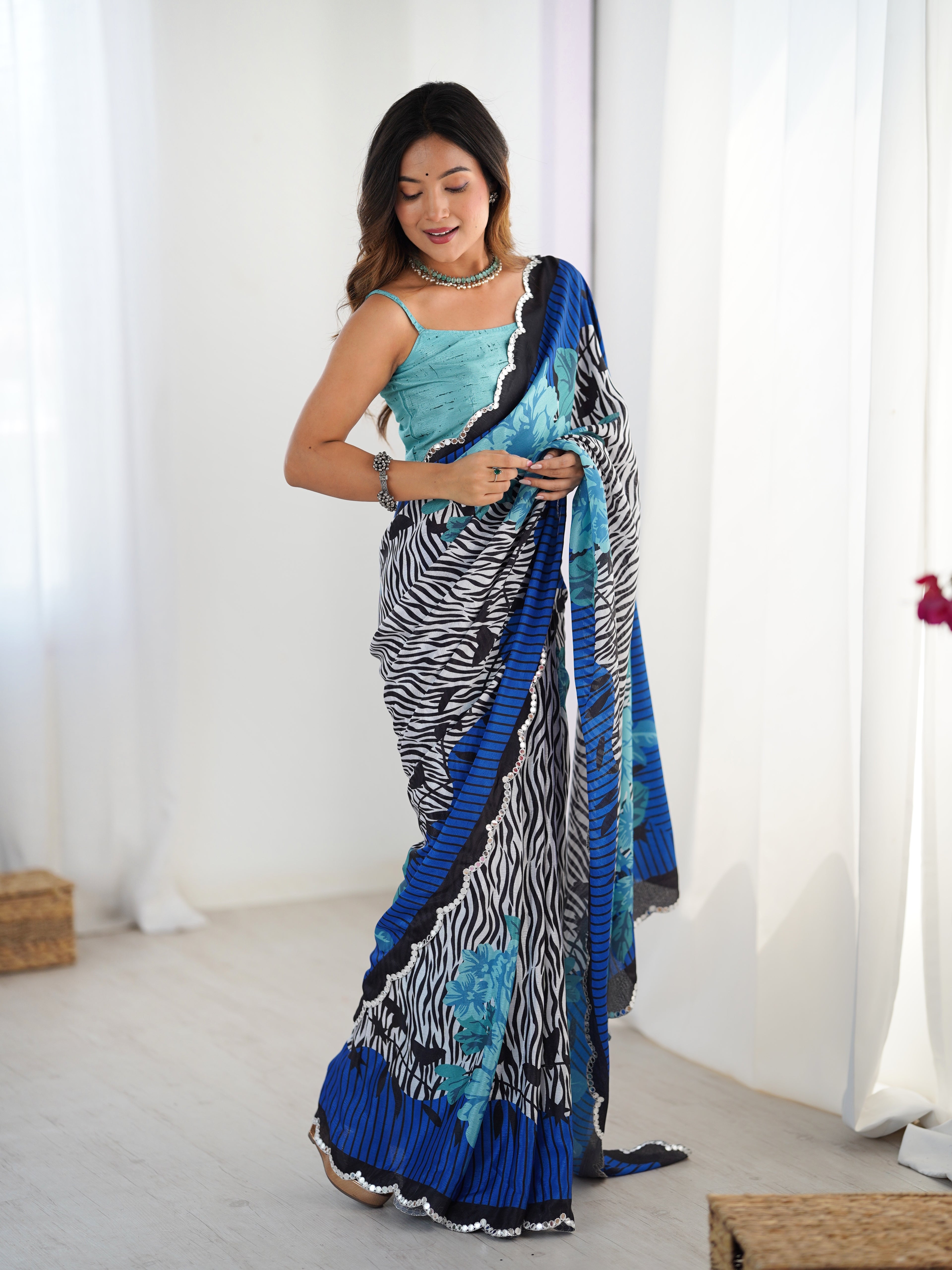 Woman wearing a colorful saree with a zebra pattern in a bright room.