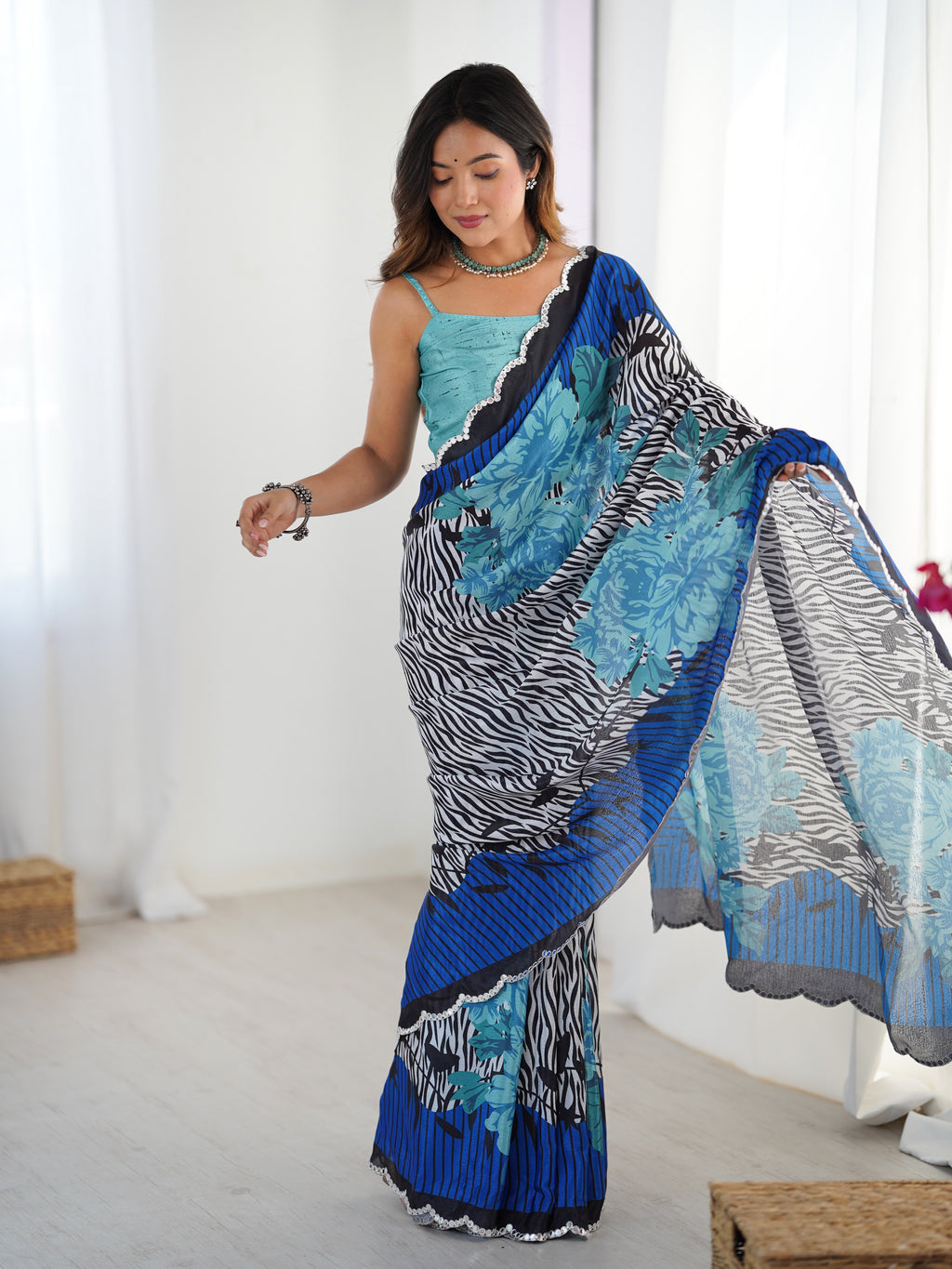 Woman wearing a blue and black patterned saree in a bright room.