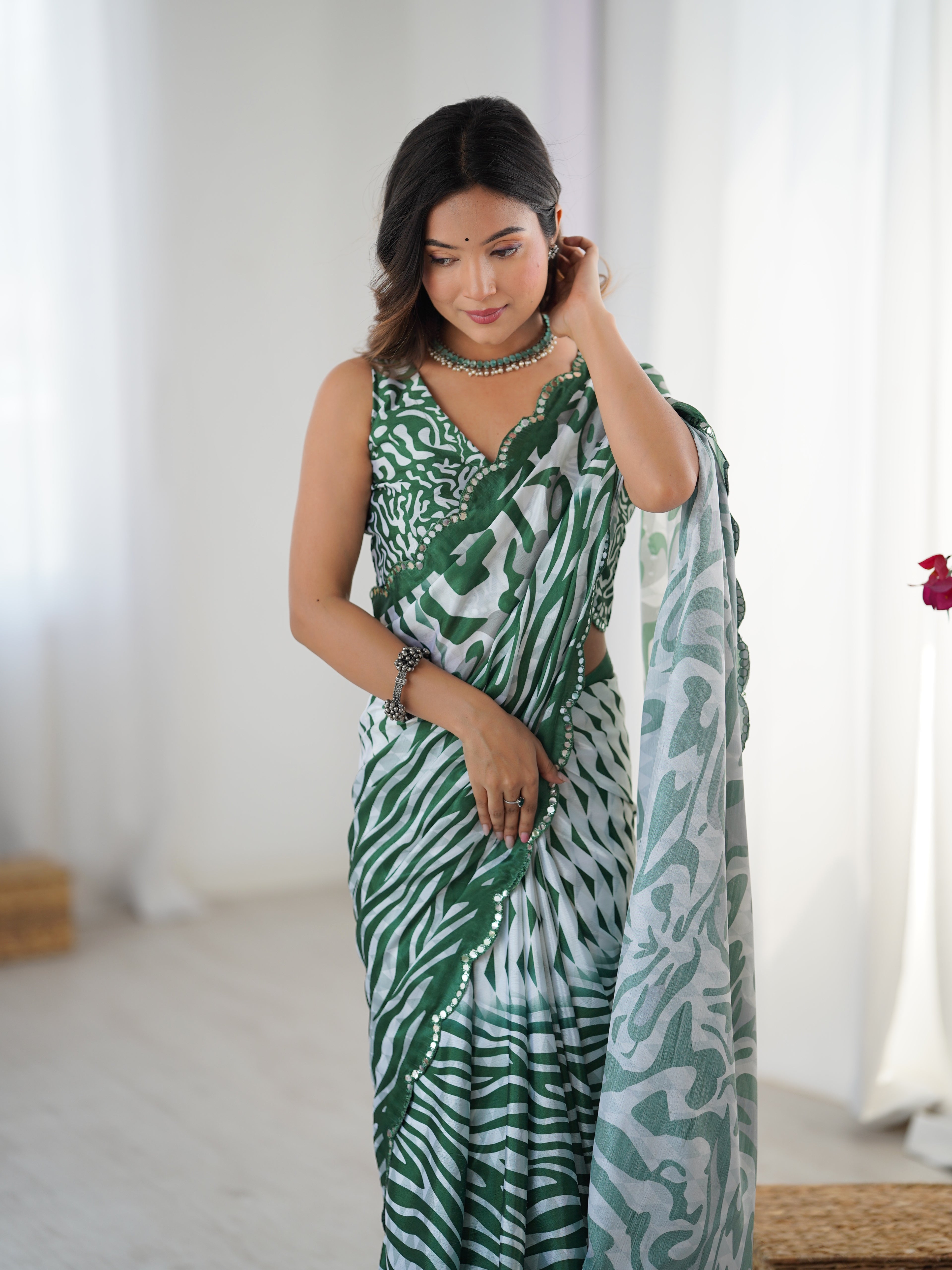 Woman wearing a green and white patterned saree in a bright room.