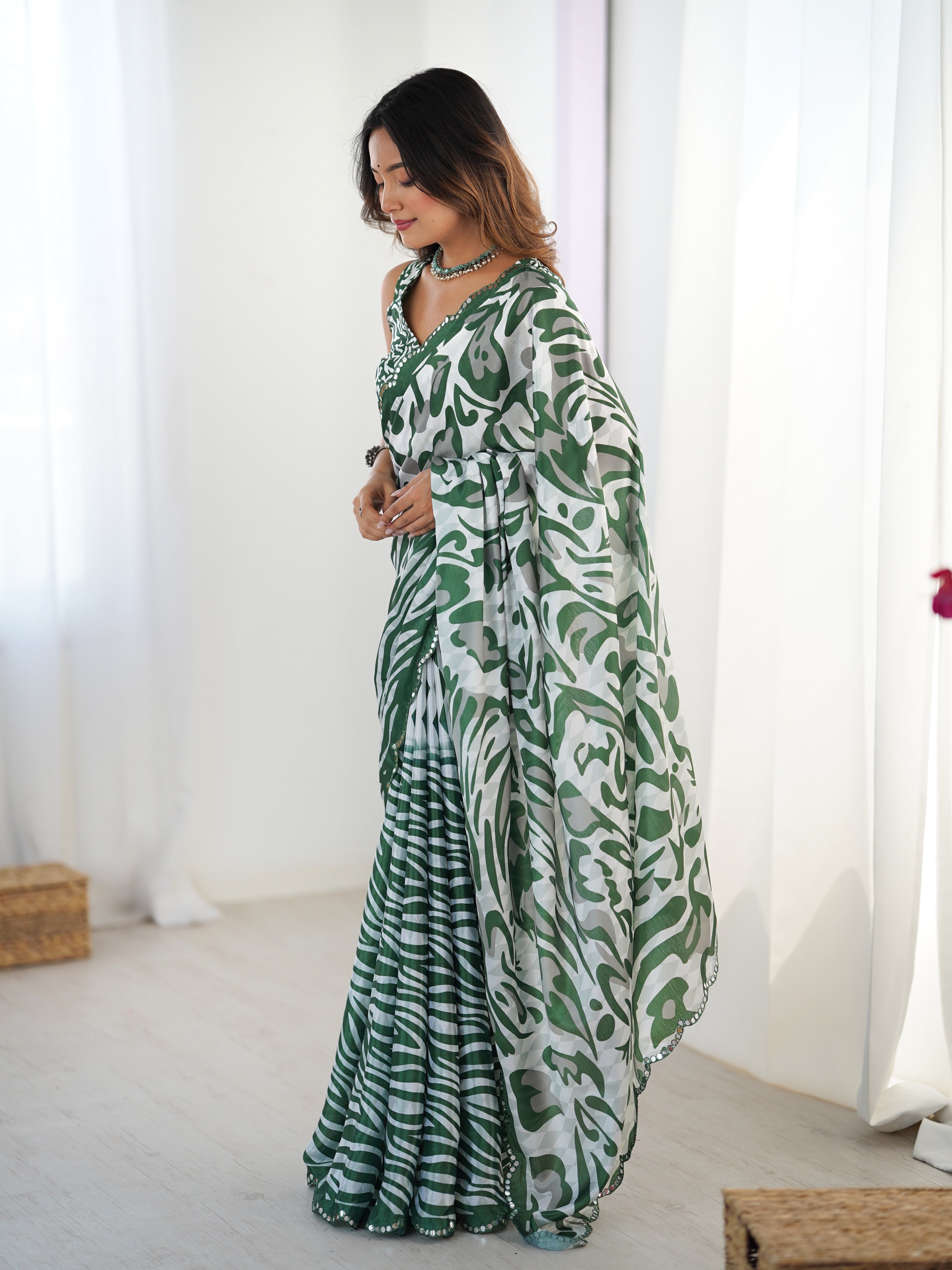 Woman wearing a green and white patterned saree in a bright room.