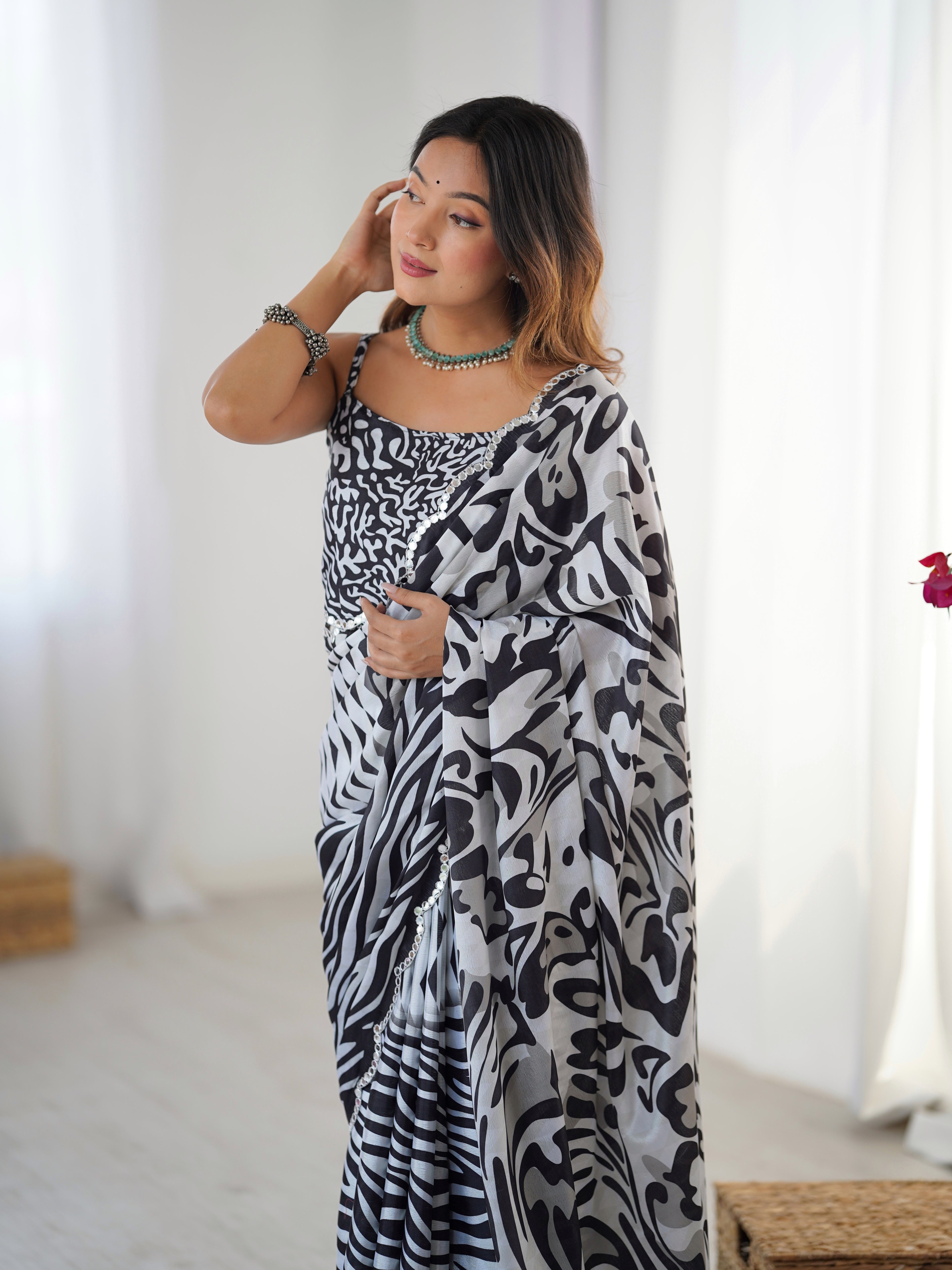 Woman wearing a black and white patterned dress with a plain background