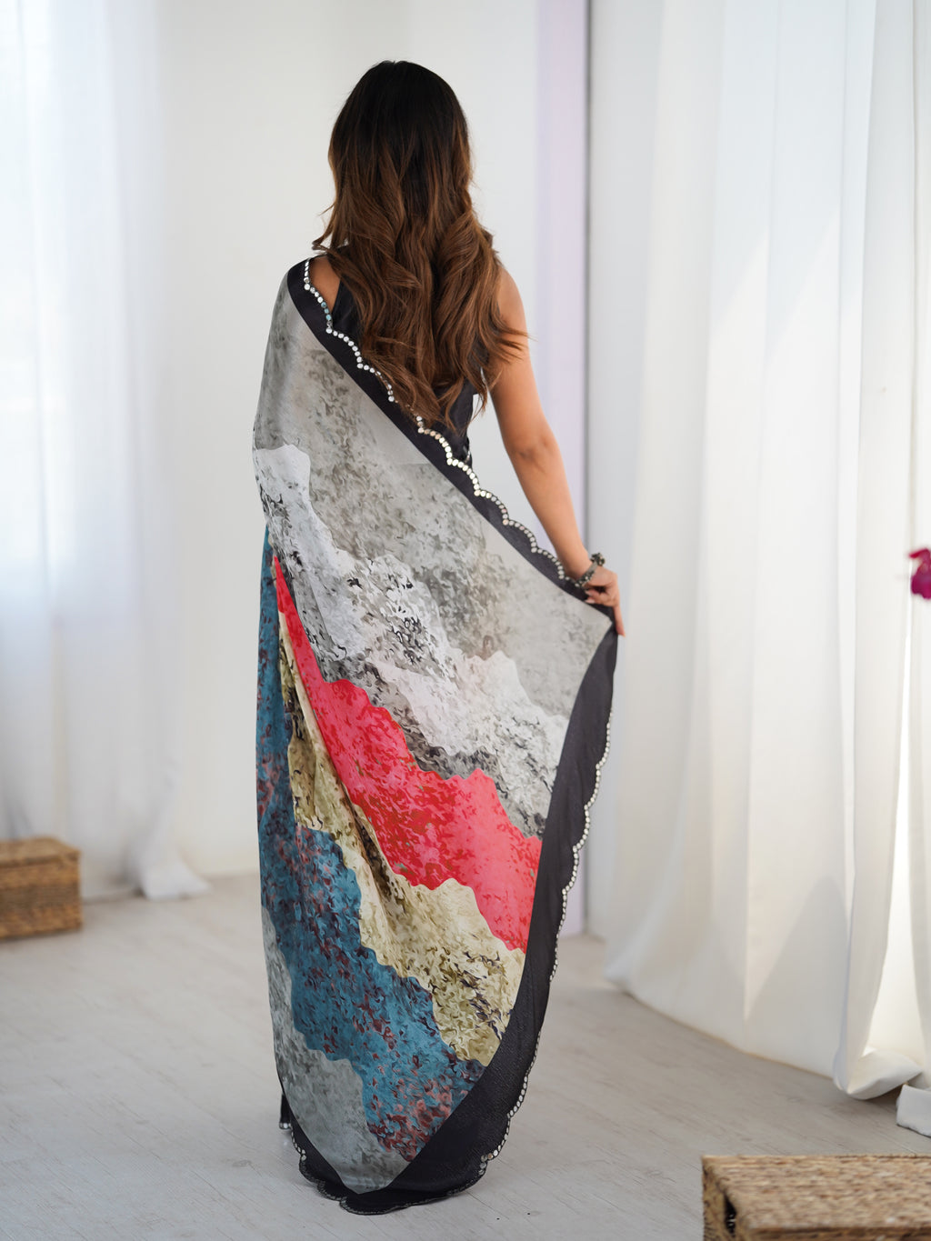 Woman holding a colorful scarf in front of white curtains
