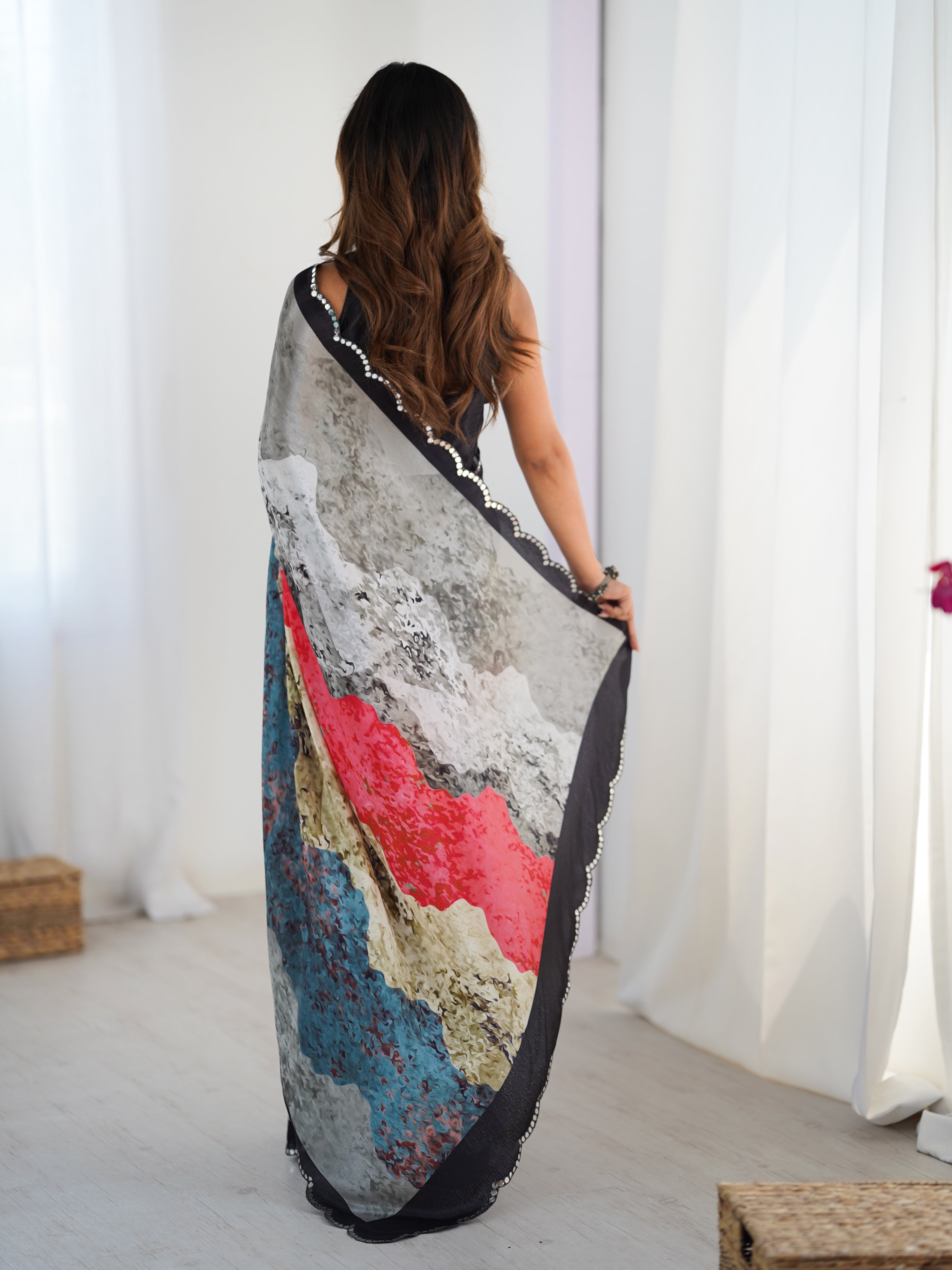 Woman holding a colorful scarf in front of white curtains