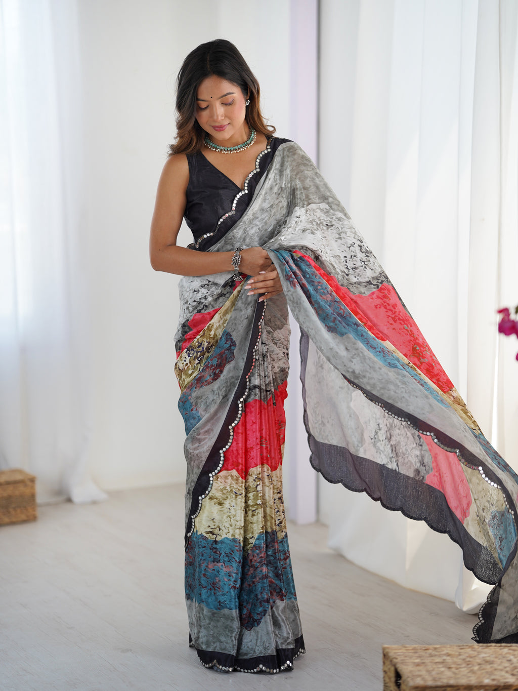 Woman wearing a colorful saree with a white curtain background