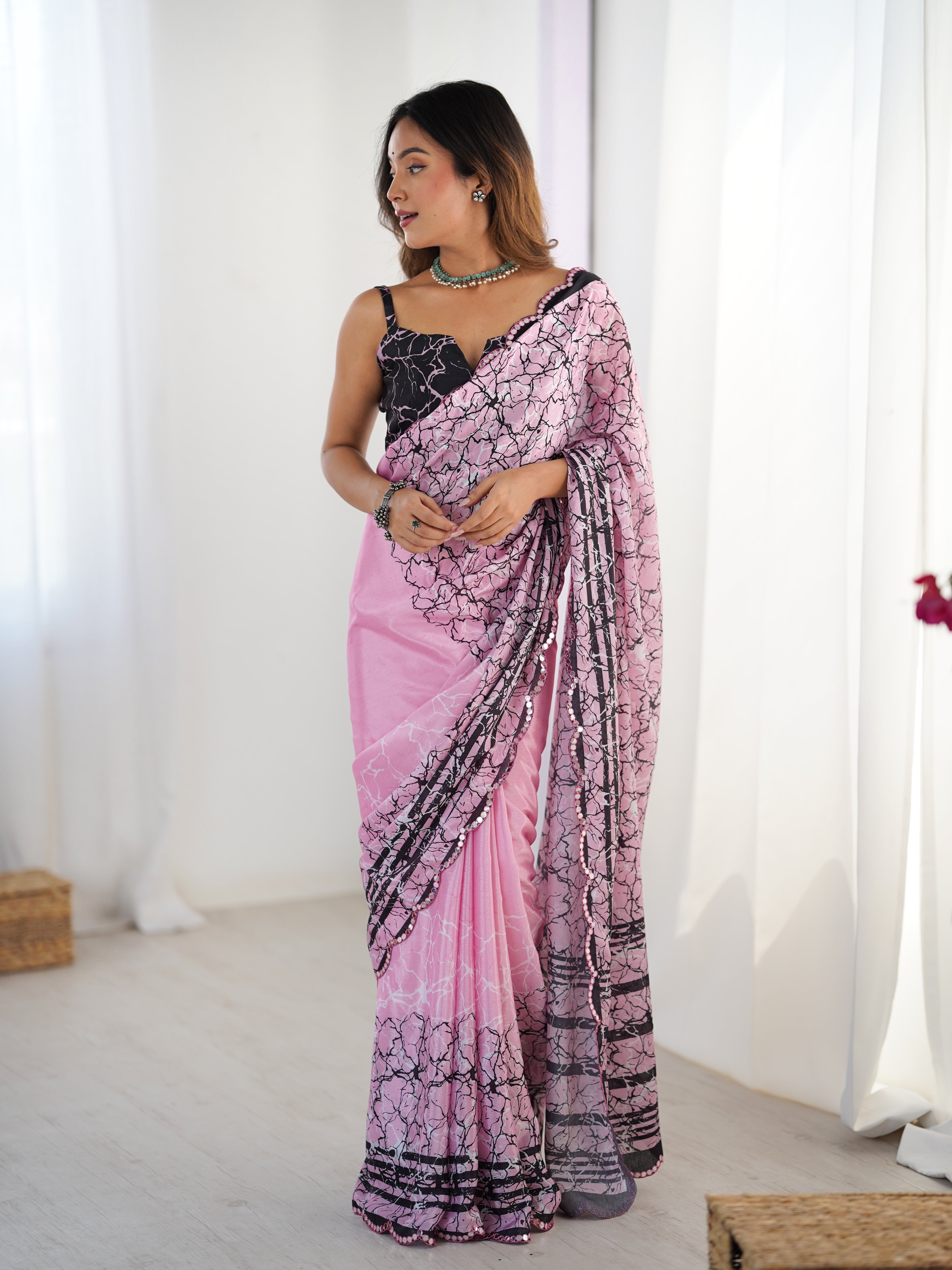 Woman wearing a pink and black saree with a white background