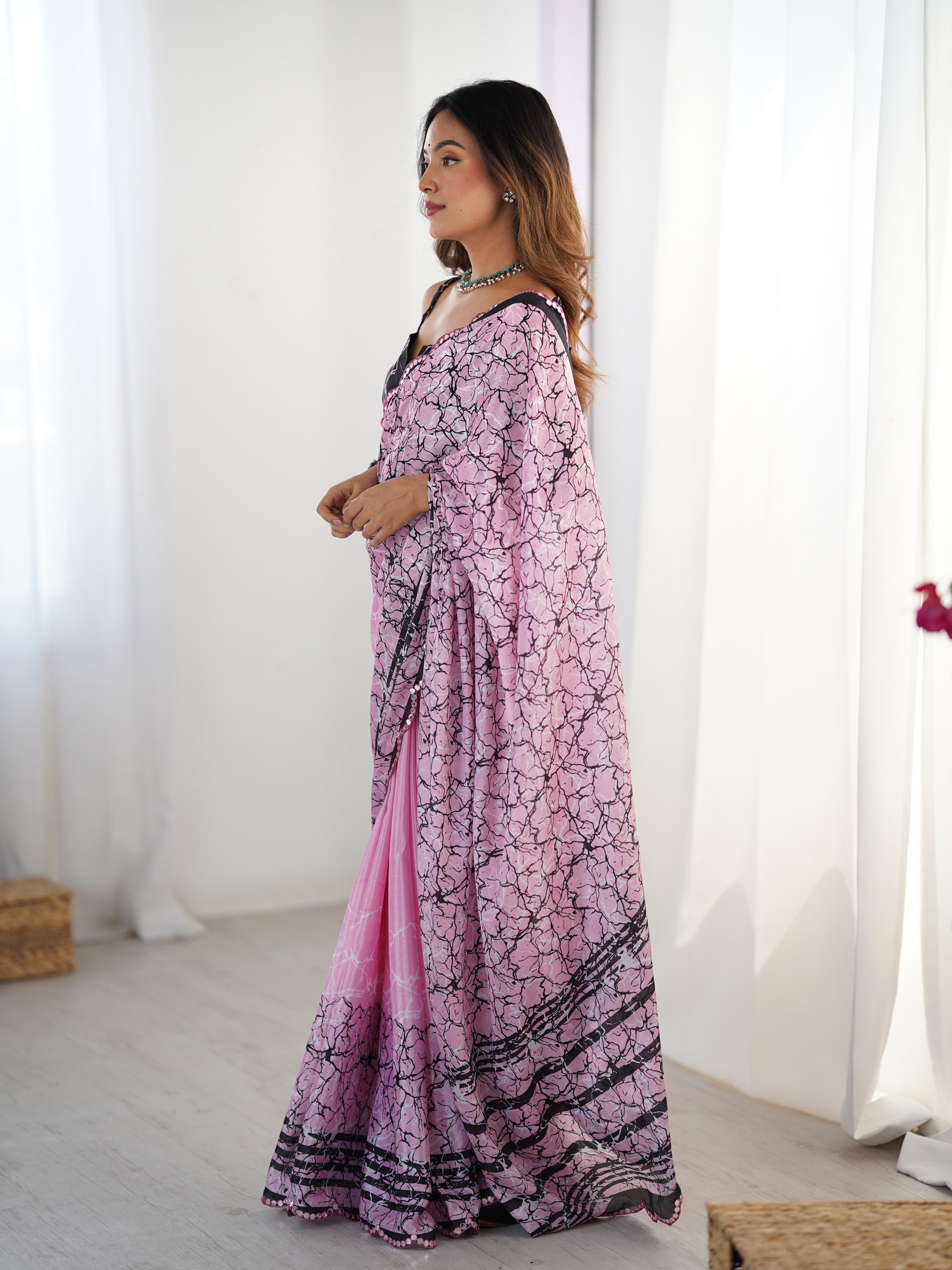 Woman wearing a pink and black patterned dress in a bright room.