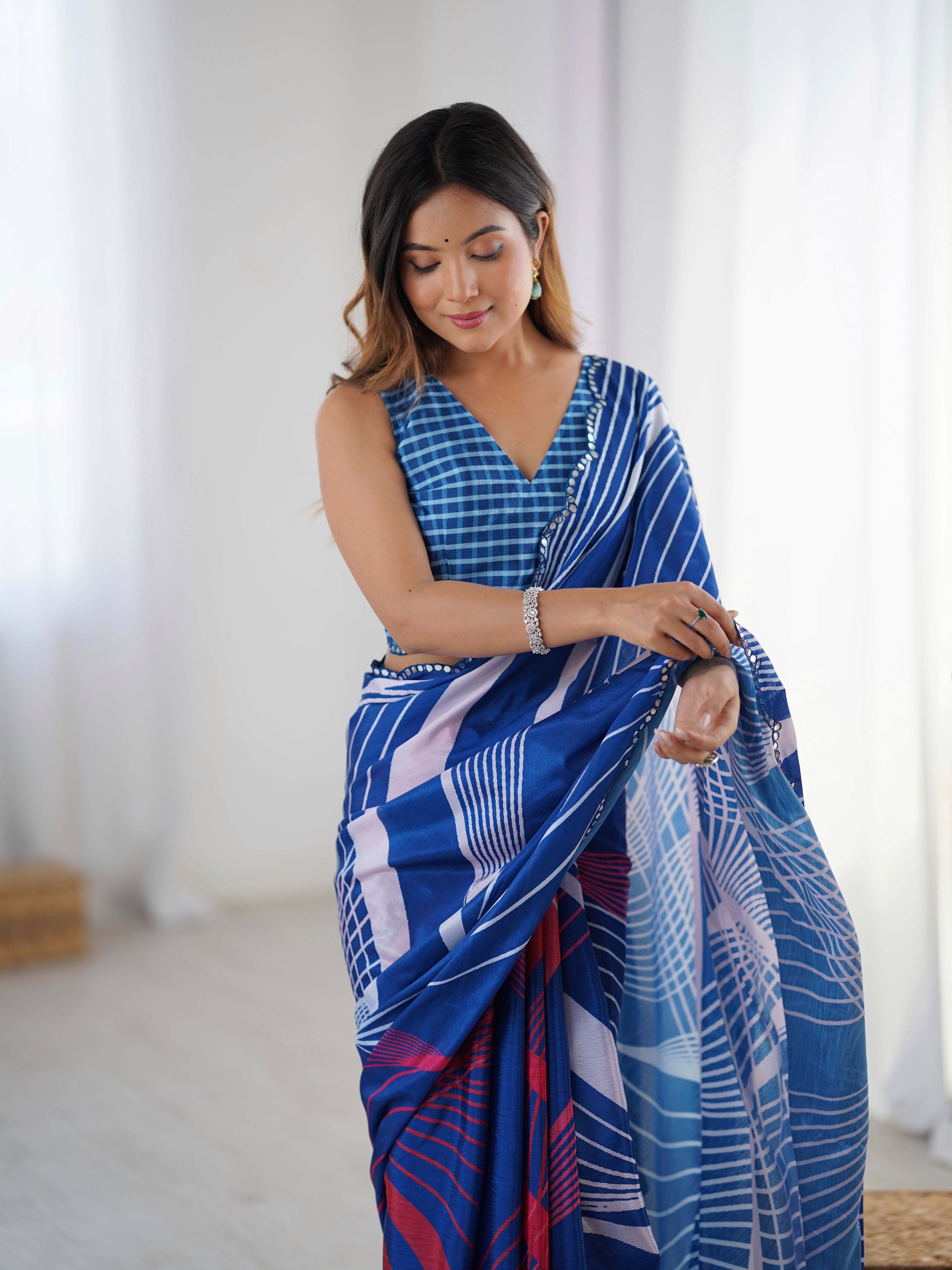 Woman wearing a blue patterned saree in a bright room
