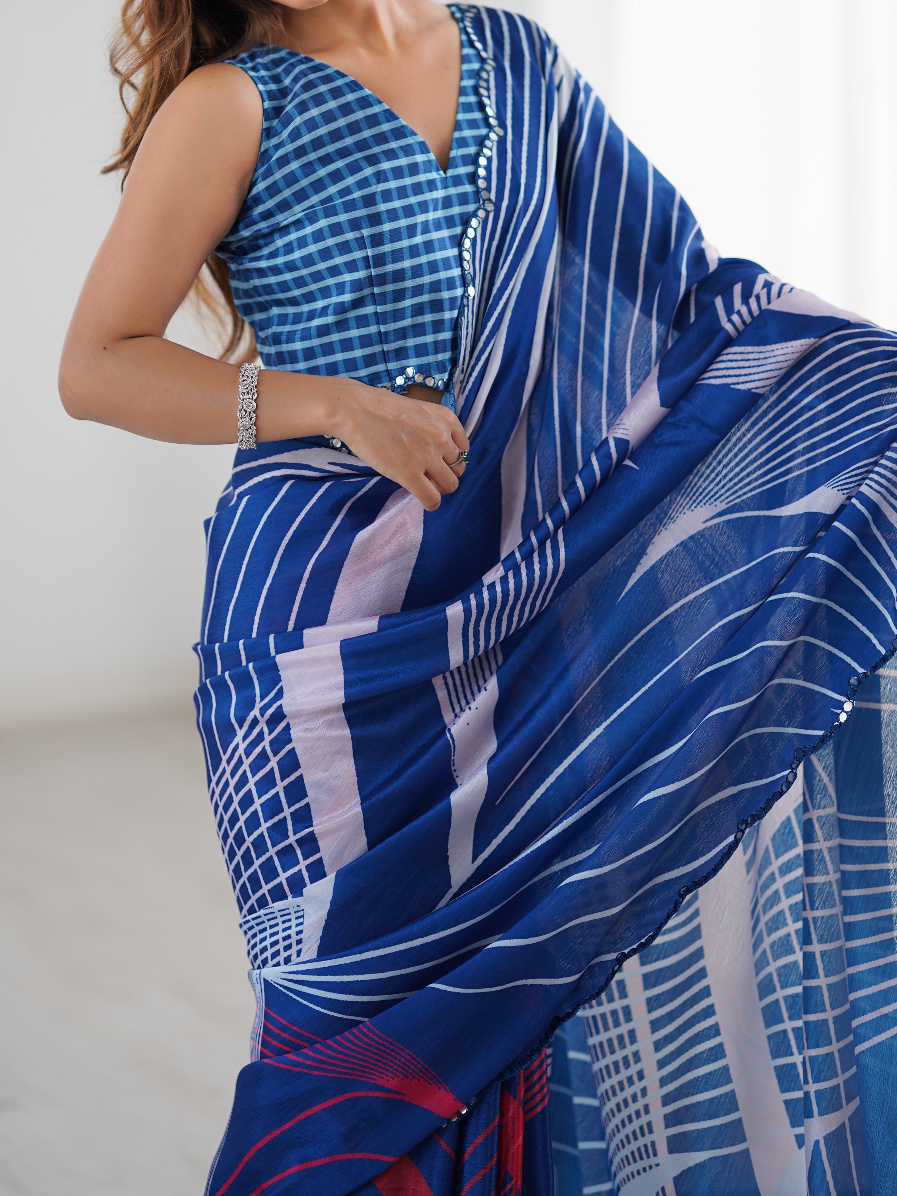 Woman wearing a blue and white patterned saree against a plain background
