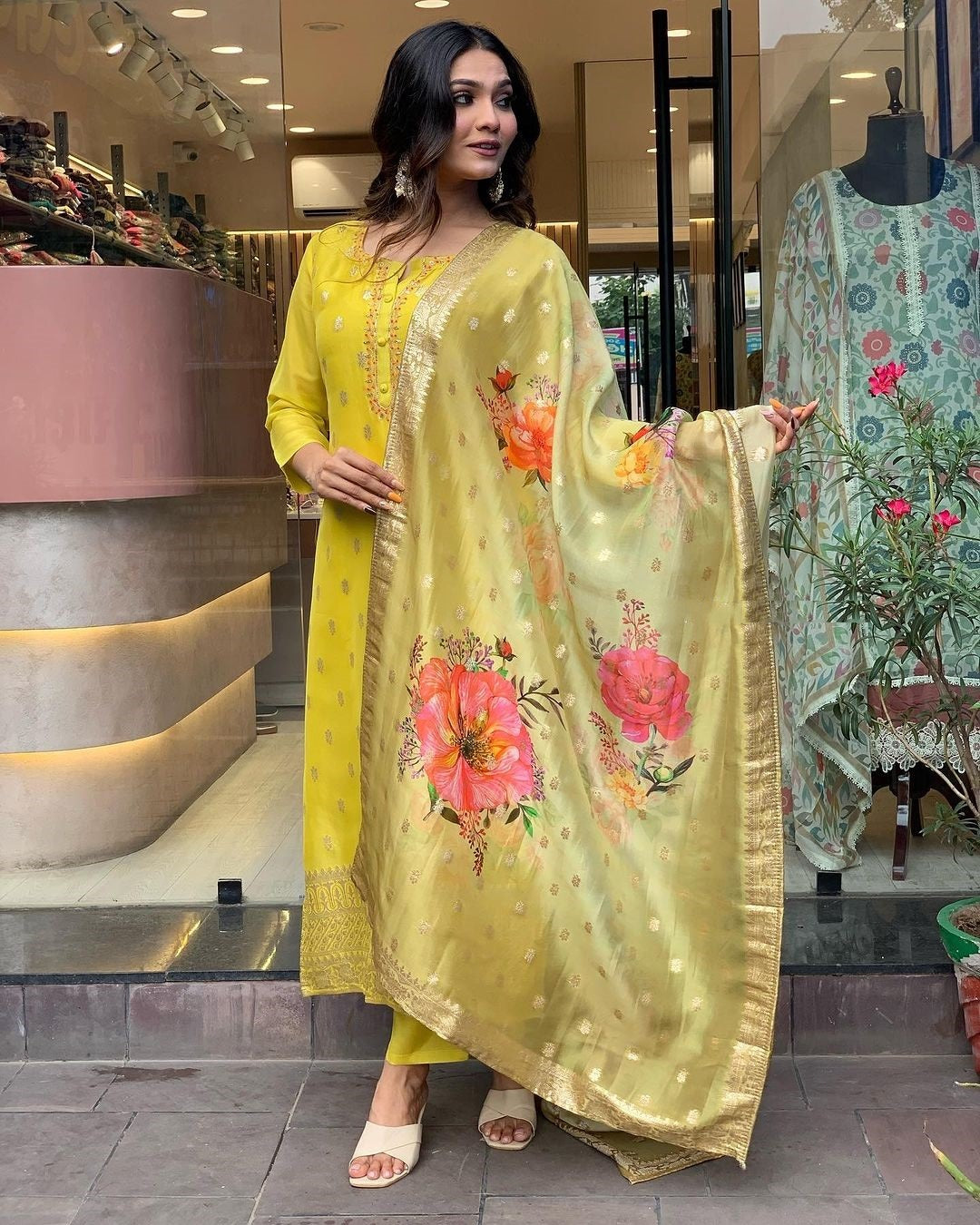 Woman in a yellow traditional kurta set outfit with floral dupatta in a store setting