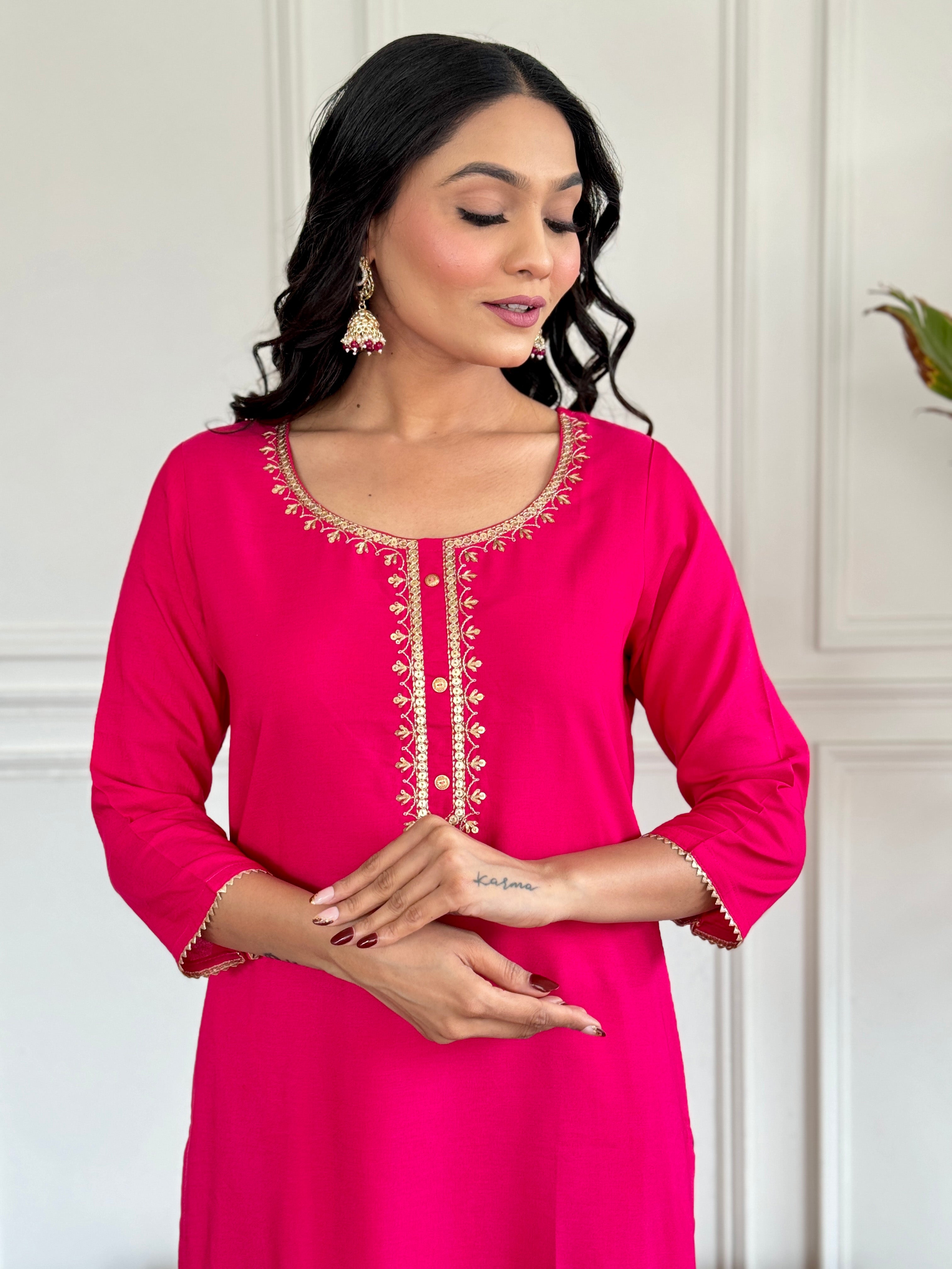 Woman wearing a pink kurta with intricate embroidery against a neutral background