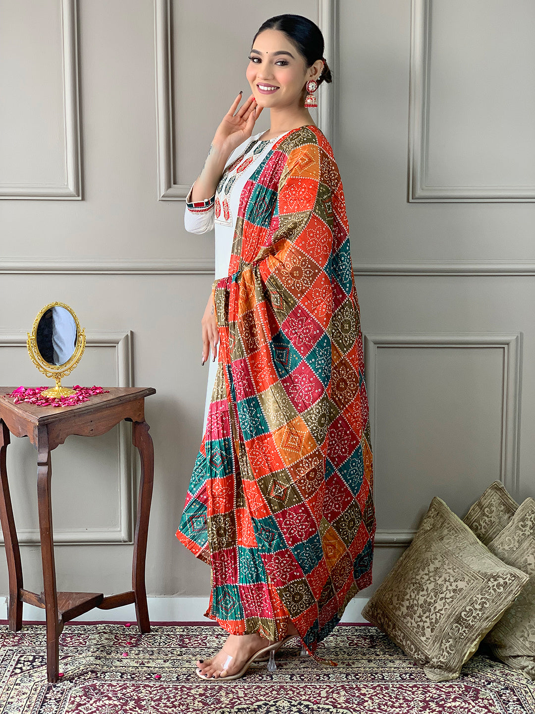 Woman wearing a colorful patterned shawl in a room with decorative elements.
