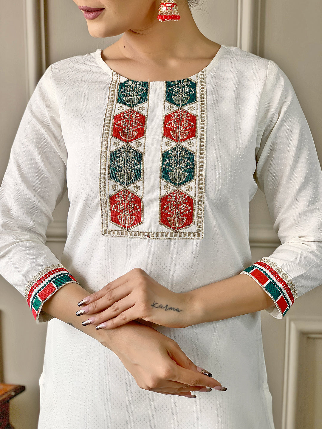 White kurta with red and green embroidery on a neutral background