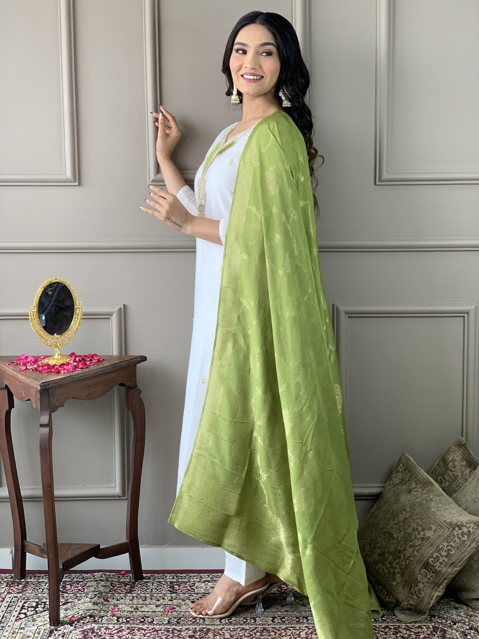 Woman wearing a white outfit with a green dupatta in an indoor setting
