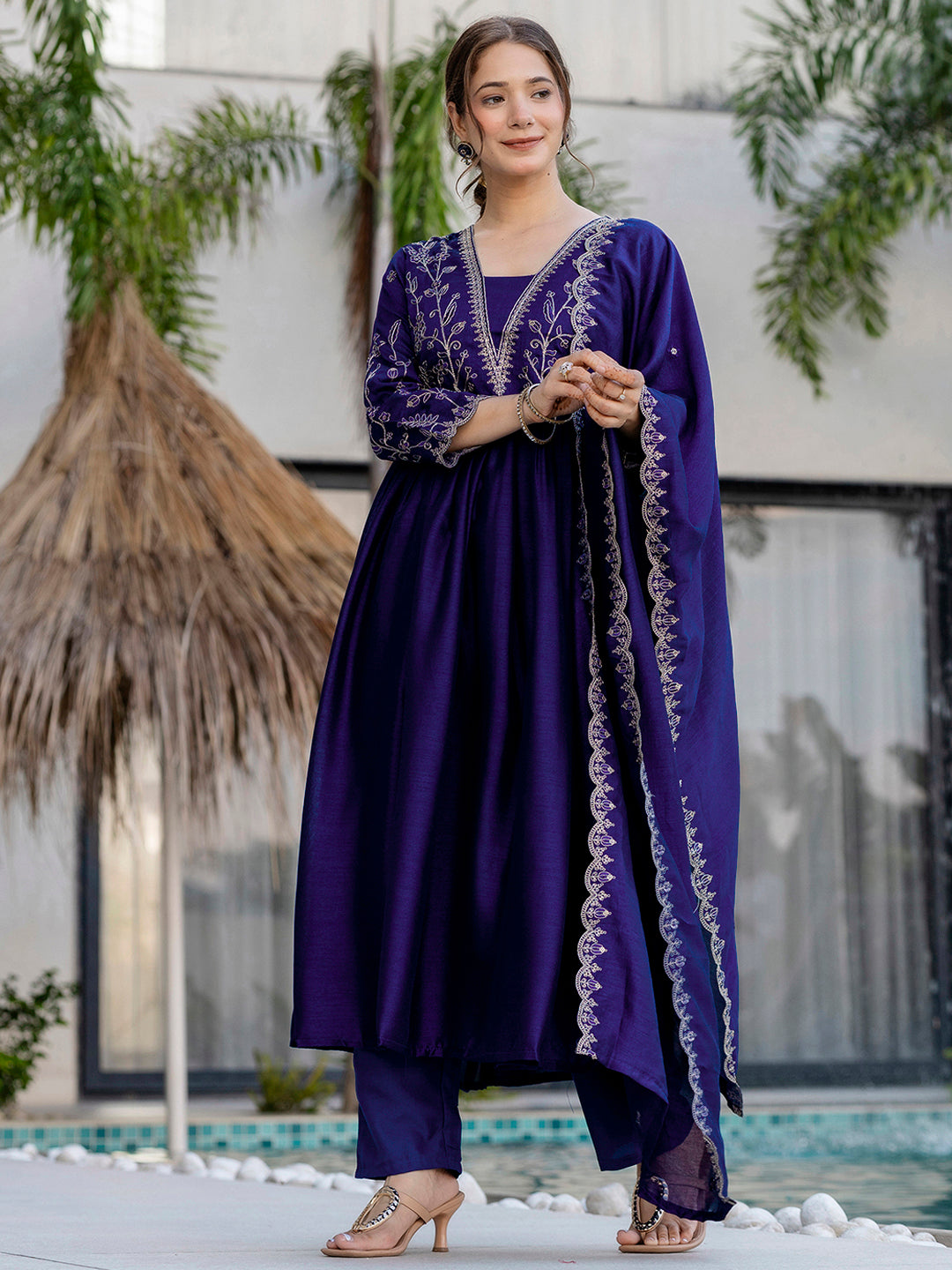 Woman wearing a purple traditional outfit with intricate designs, standing outdoors.