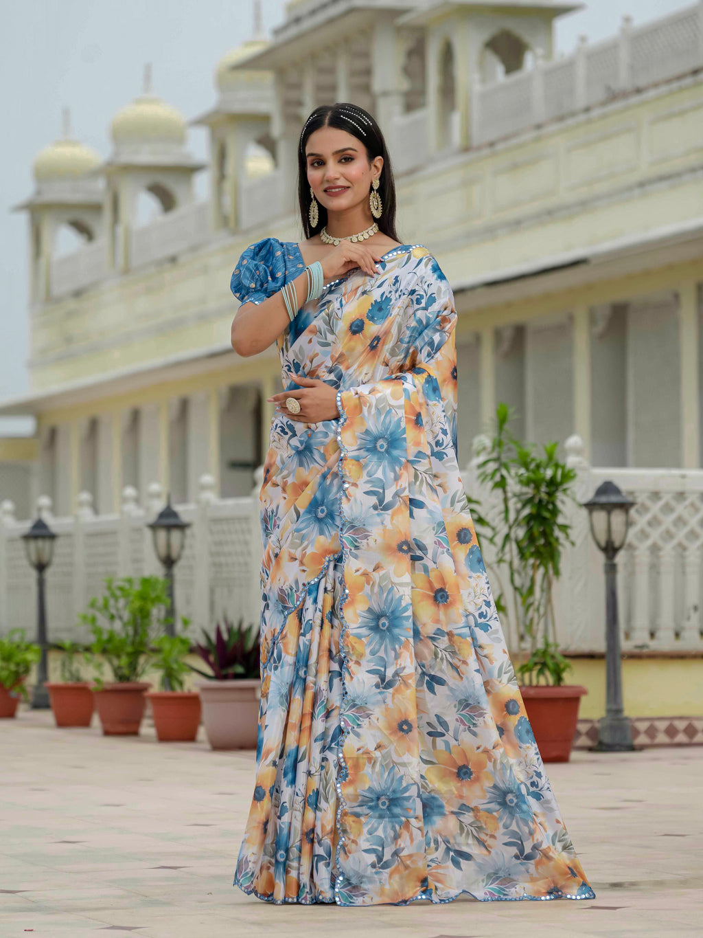 Woman in a ready to wear saree standing in front of a building with decorative elements.