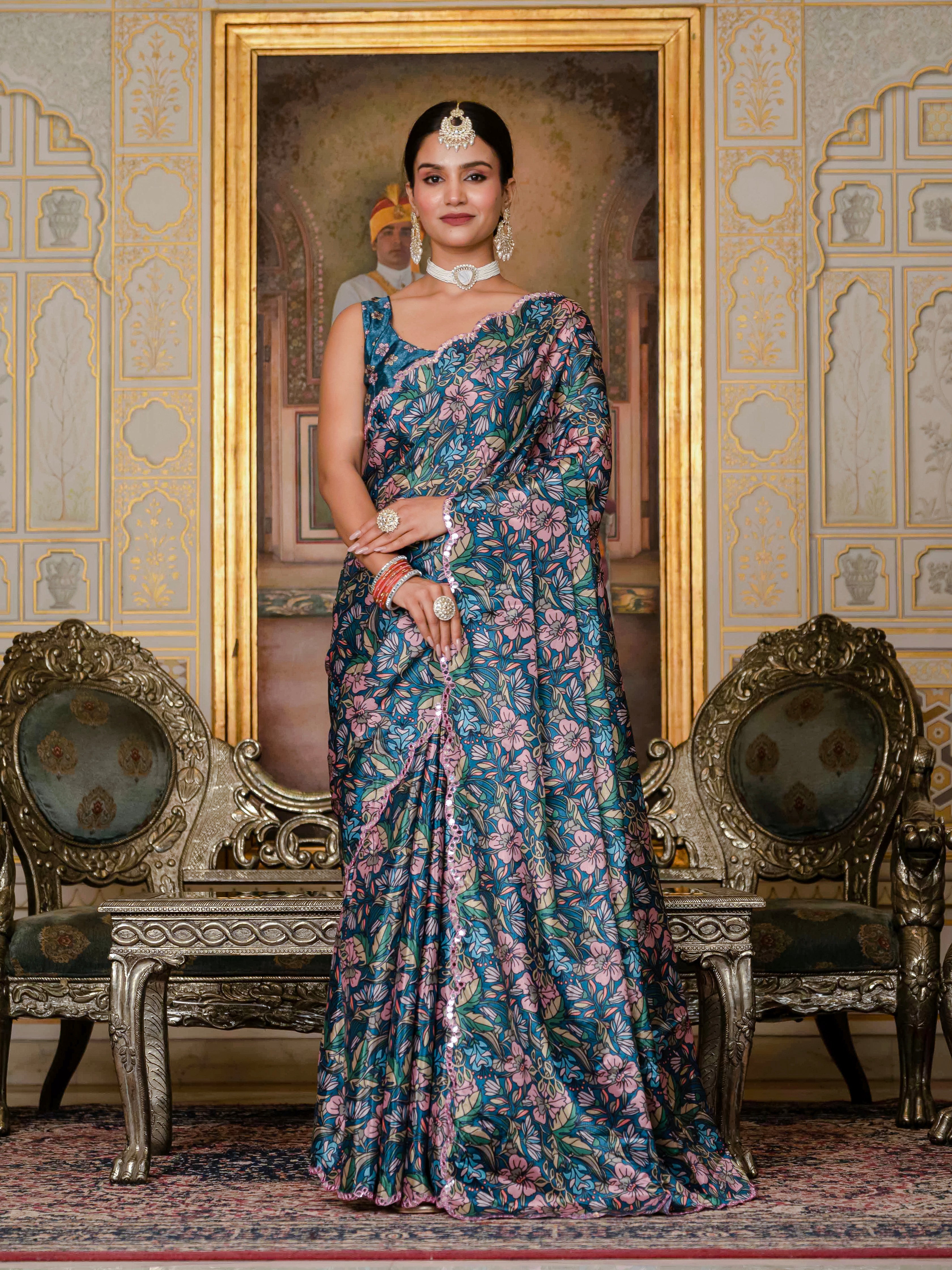Peacock Blue with soft pastel floral prints in shades of blush pink, lavender, sage green, and muted beige, finished with a mirror lace border.