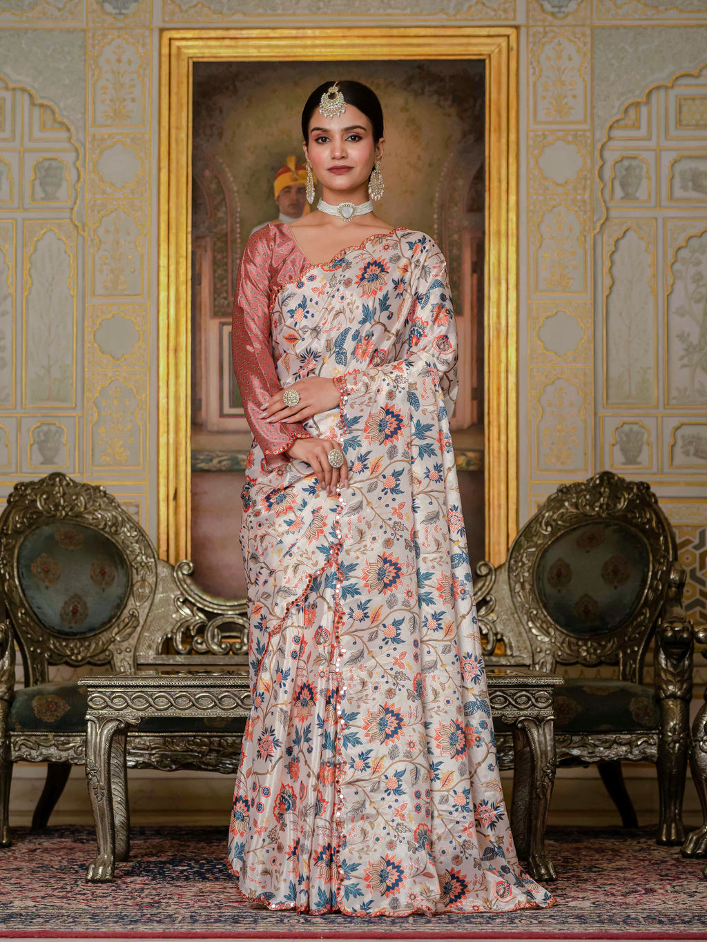 A woman wearing a ready-to-wear saree stands in an ornate room adorned with decorative walls and elegant furniture.