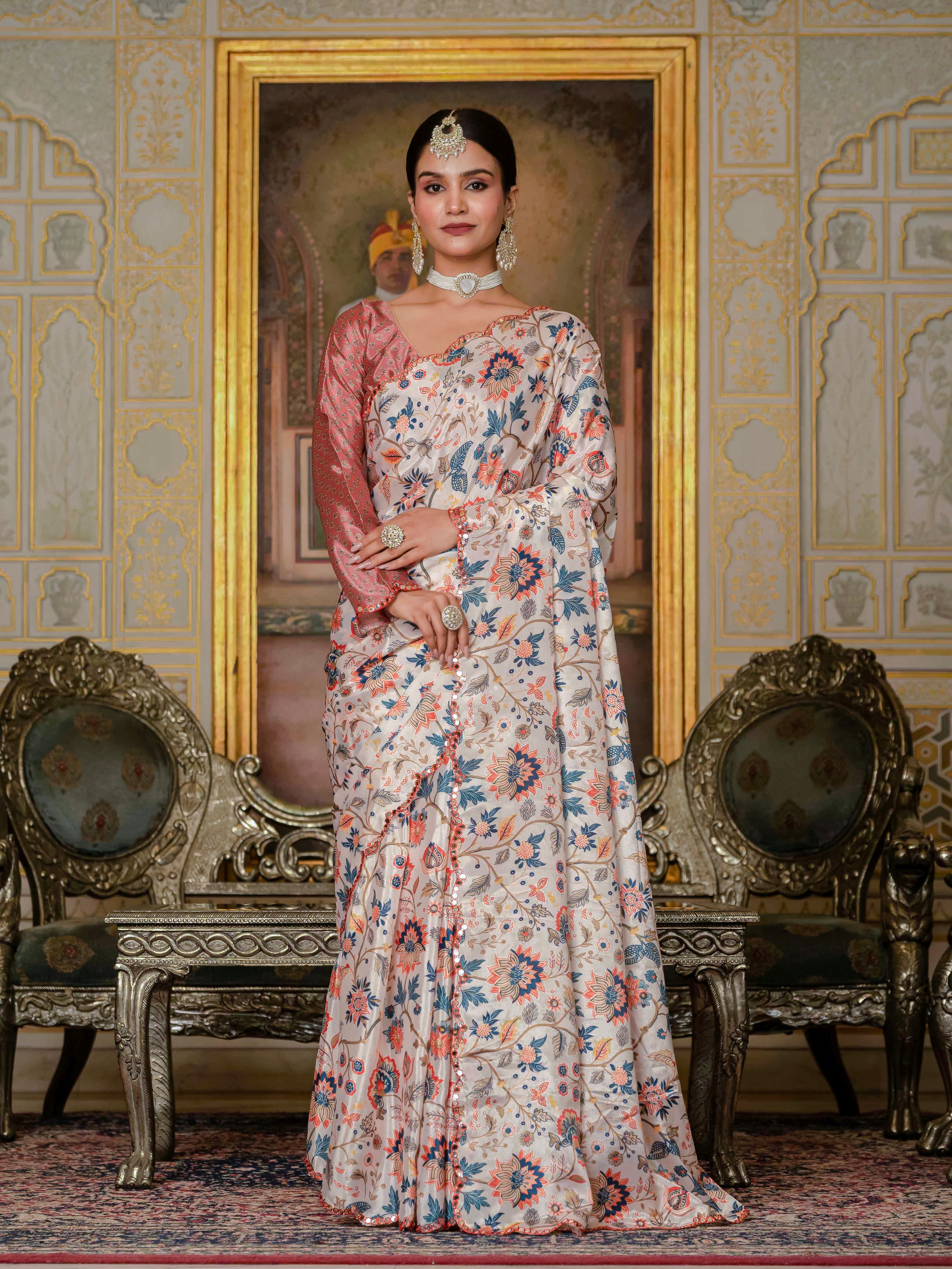 A woman wearing a ready-to-wear saree stands in an ornate room adorned with decorative walls and elegant furniture.