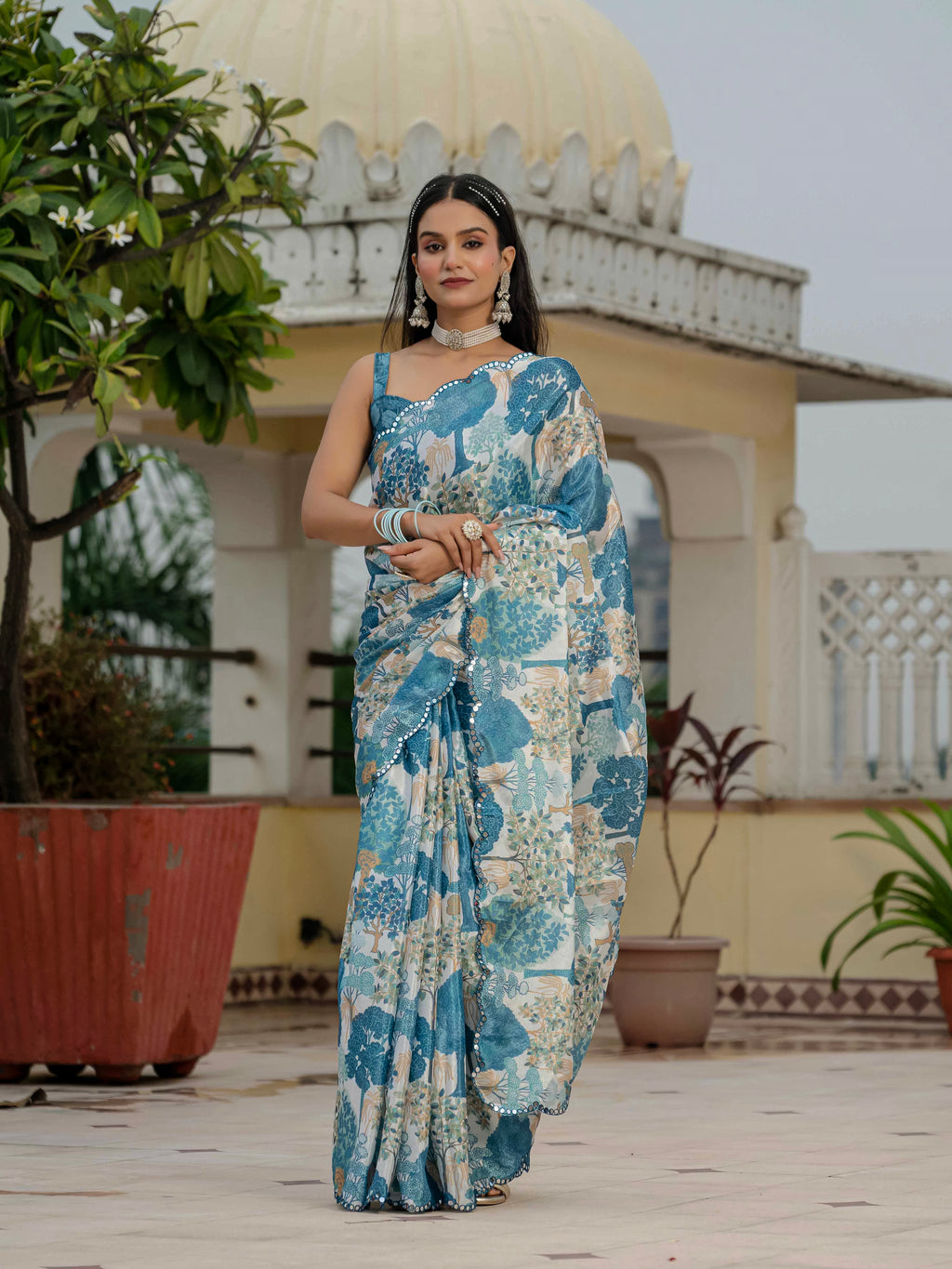 Woman in a blue ready to wear saree standing outdoors with architectural background
