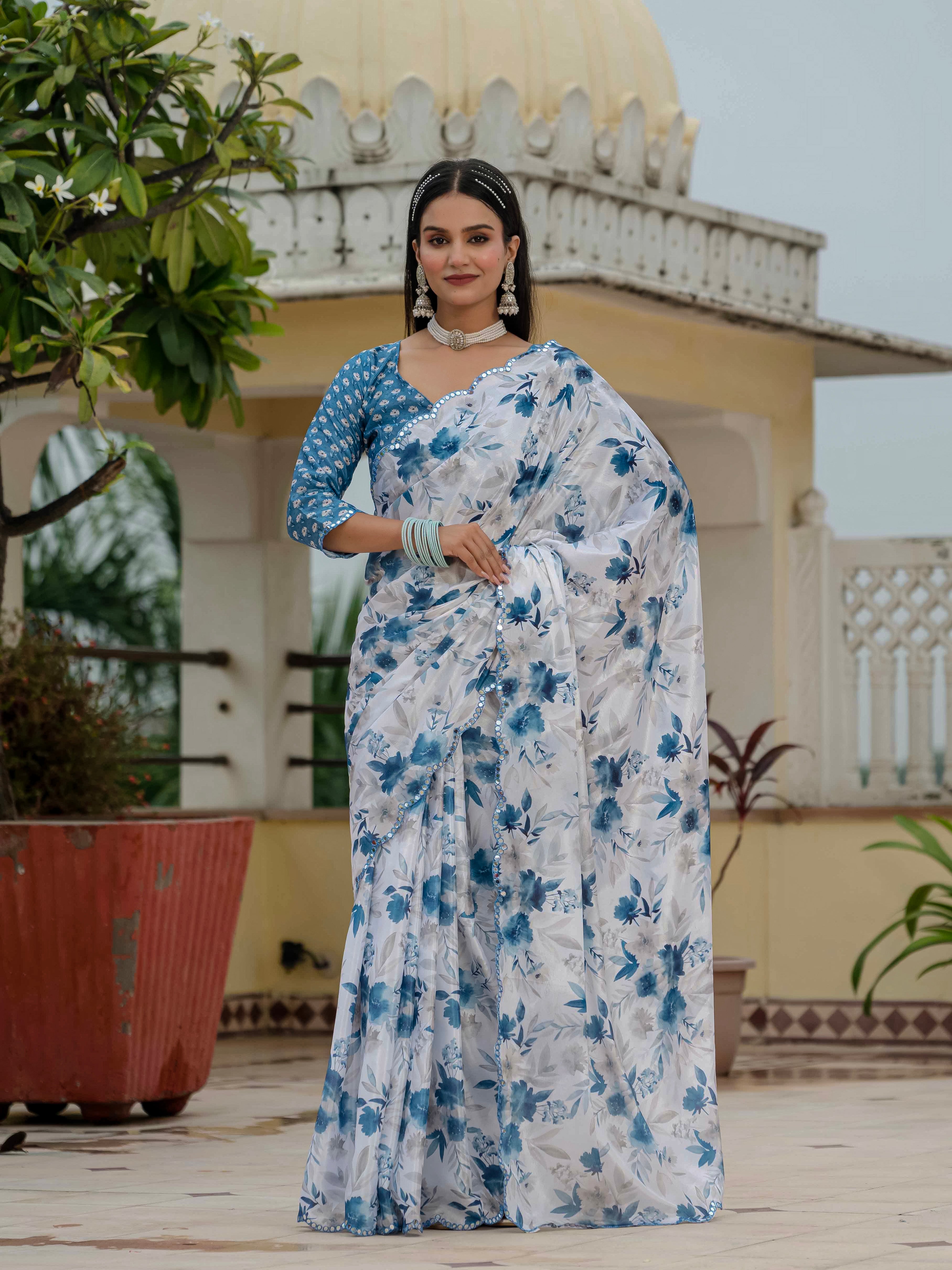 Woman in a blue and white ready to wear saree standing outdoors with architectural background