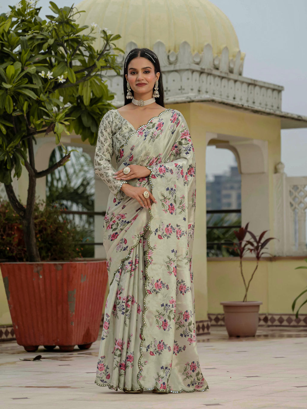 Woman in a ready to wear saree standing on a rooftop with architectural elements and plants in the background