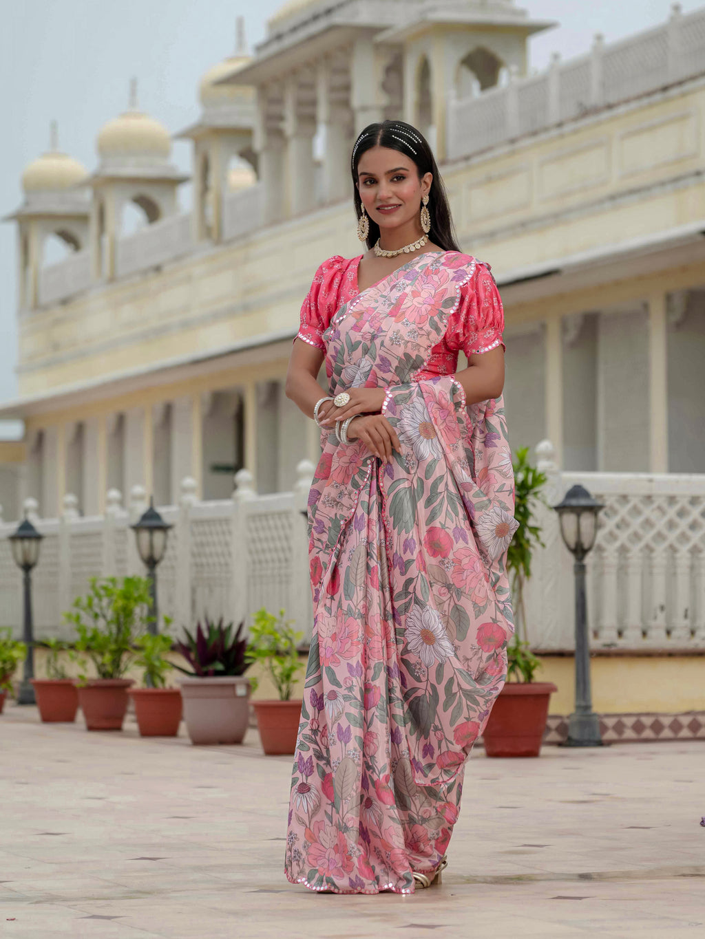 Woman in a ready to wear saree standing in front of a traditional building.