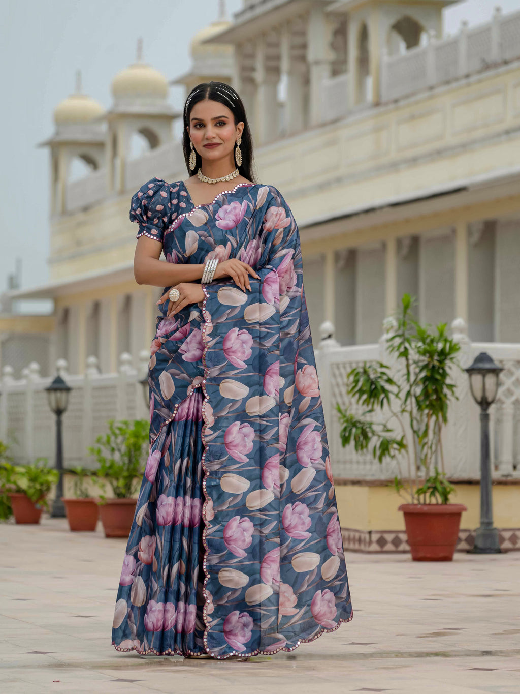 Woman in a ready to wear saree standing in front of a building with architectural elements.