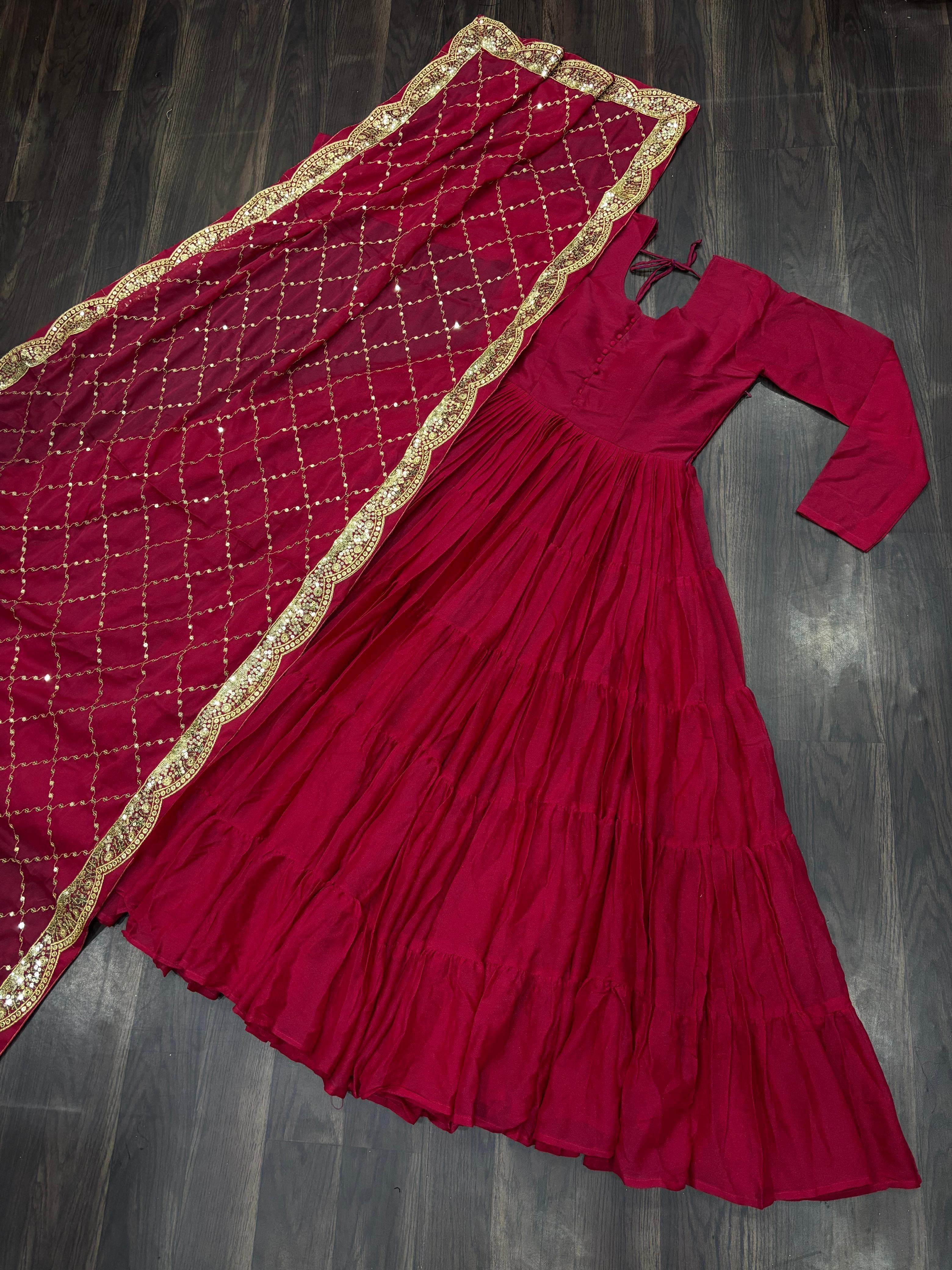 Red anarkali gown or dress with long sleeves and a matching red dupatta draped over it on a dark wooden surface.